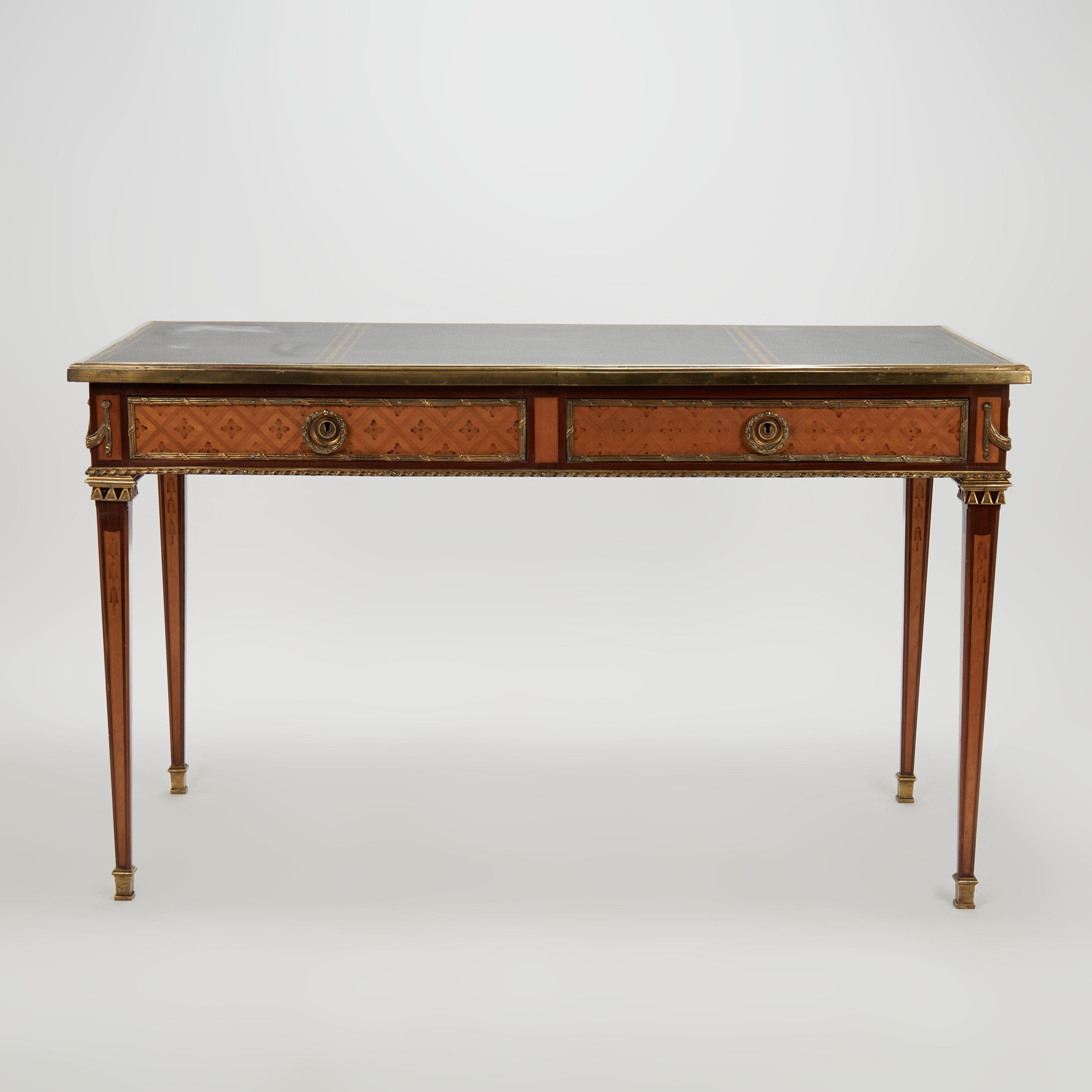Impressive antique French desk crafted in mahogany and tulipwood, featuring a top with three tooled leather panels banded in brass on a case with two pullout leather top trays and two drawers with inlaid geometric and floral motifs highlighted with