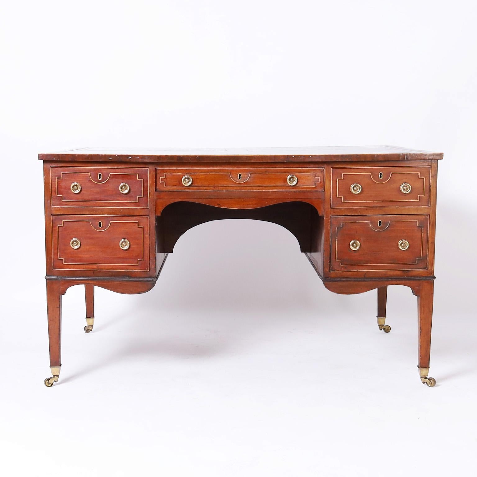 Impressive 19th century French partners desk with a tooled red leather top over a case crafted in mahogany with four drawers on either side decorated with beaded geometric designs, featuring a scrolled skirt and tapered legs on brass casters.
