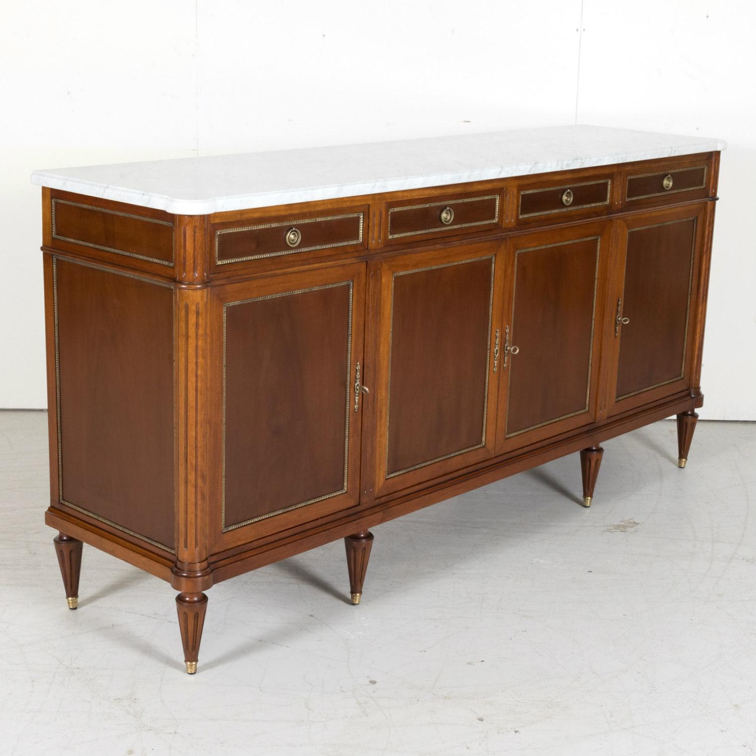 Early 20th century French Louis XVI style enfilade buffet handcrafted of mahogany by skilled craftsmen near Paris, circa 1900. Having a white molded Carrara marble top with cookie cutter corners over four drawers and four paneled doors, all with