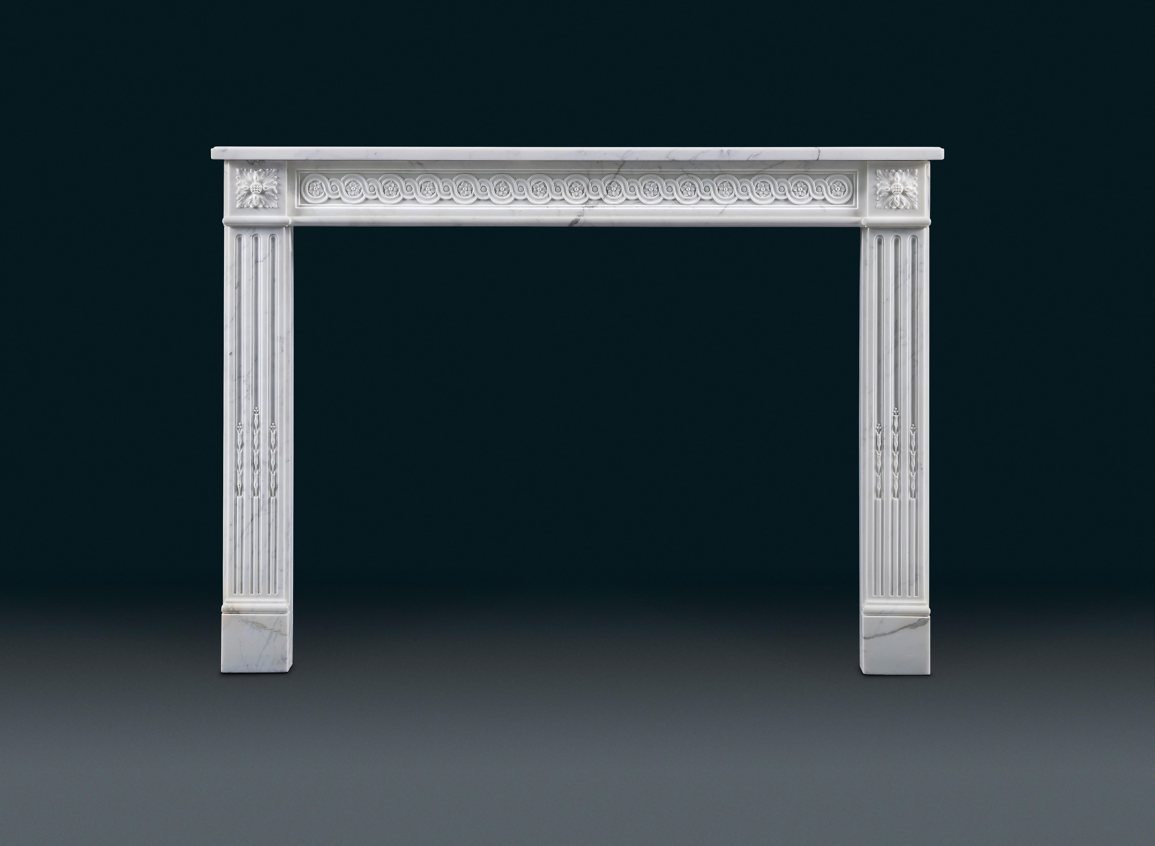 An antique 19th century, French Louis XVI style, veined white marble fireplace with simple rectangular shelf. The panelled frieze decorated with intertwining guilloche centred with flowers, the jambs with three stopped flutes surmounted by scalloped