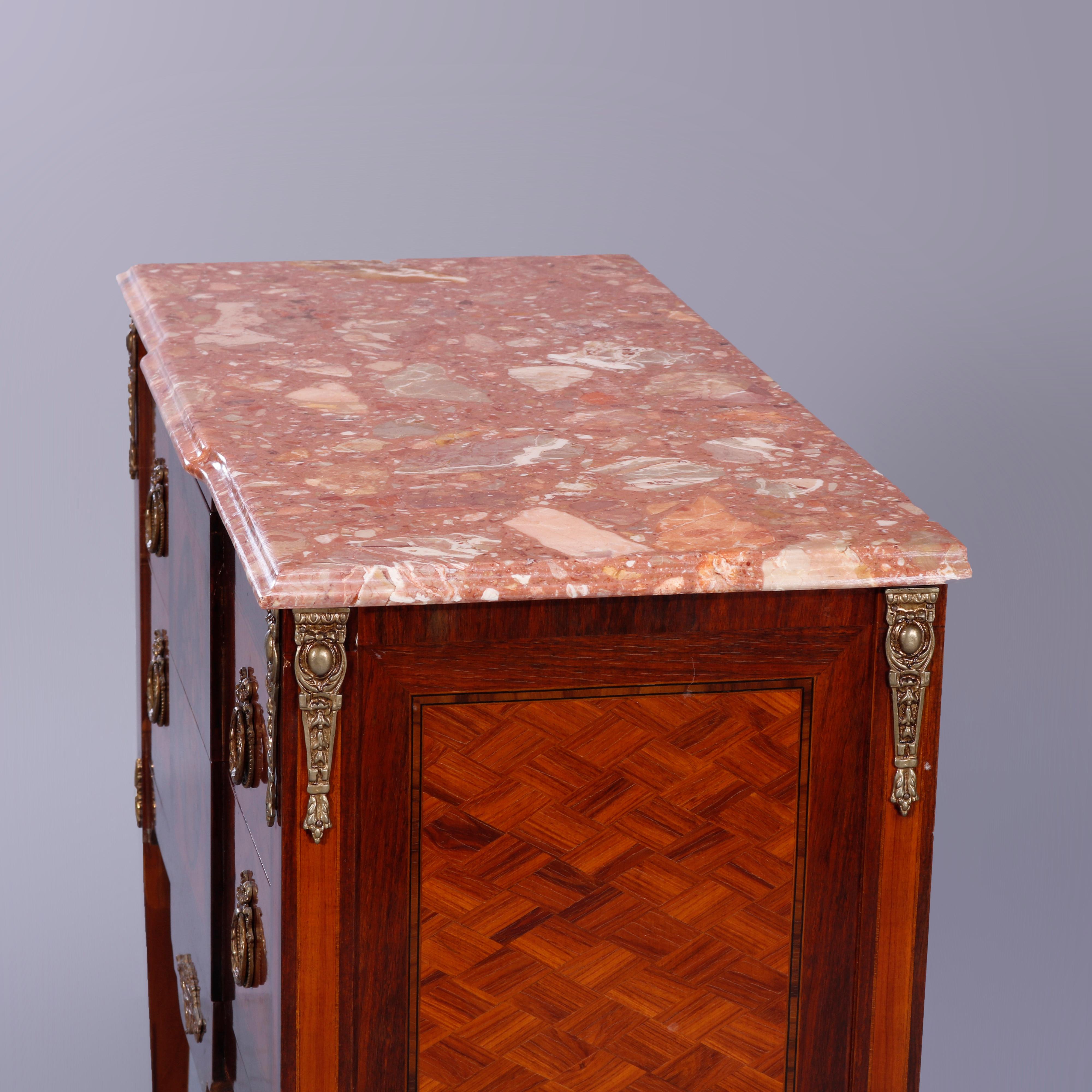 An antique French Louis XVI style commode offers beveled marble top over double drawer commode having kingwood and rosewood construction, parquetry panels, central marquetry inlaid panier de fleurs (basket of flowers), and foliate cast ormolu