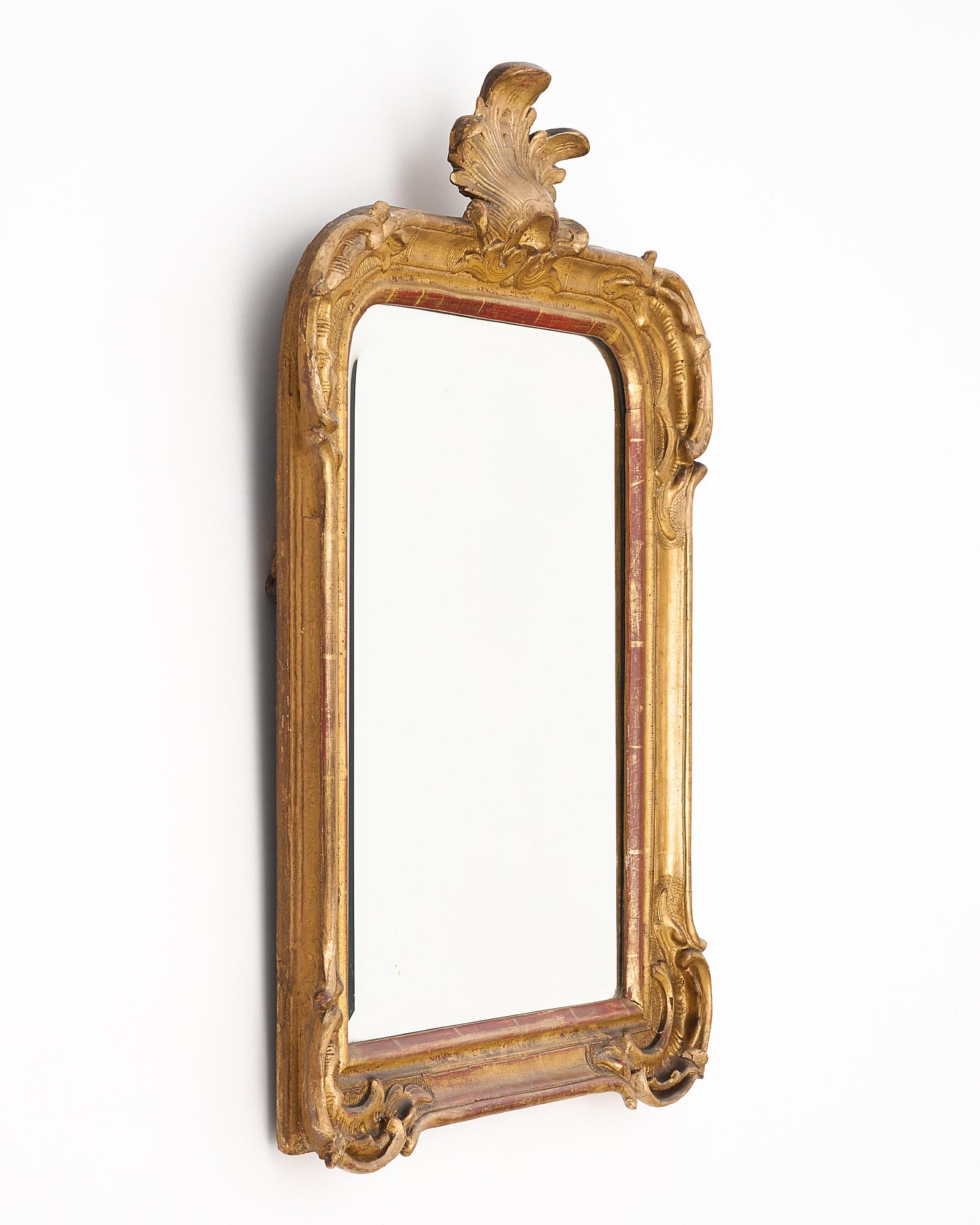 French Louis XVI mirror made of stuccoed hand-carved wood with “foliage” fronton and its original beveled mirror. The original 24 carat gold leafing lets the warm terracotta under tone shine through.
