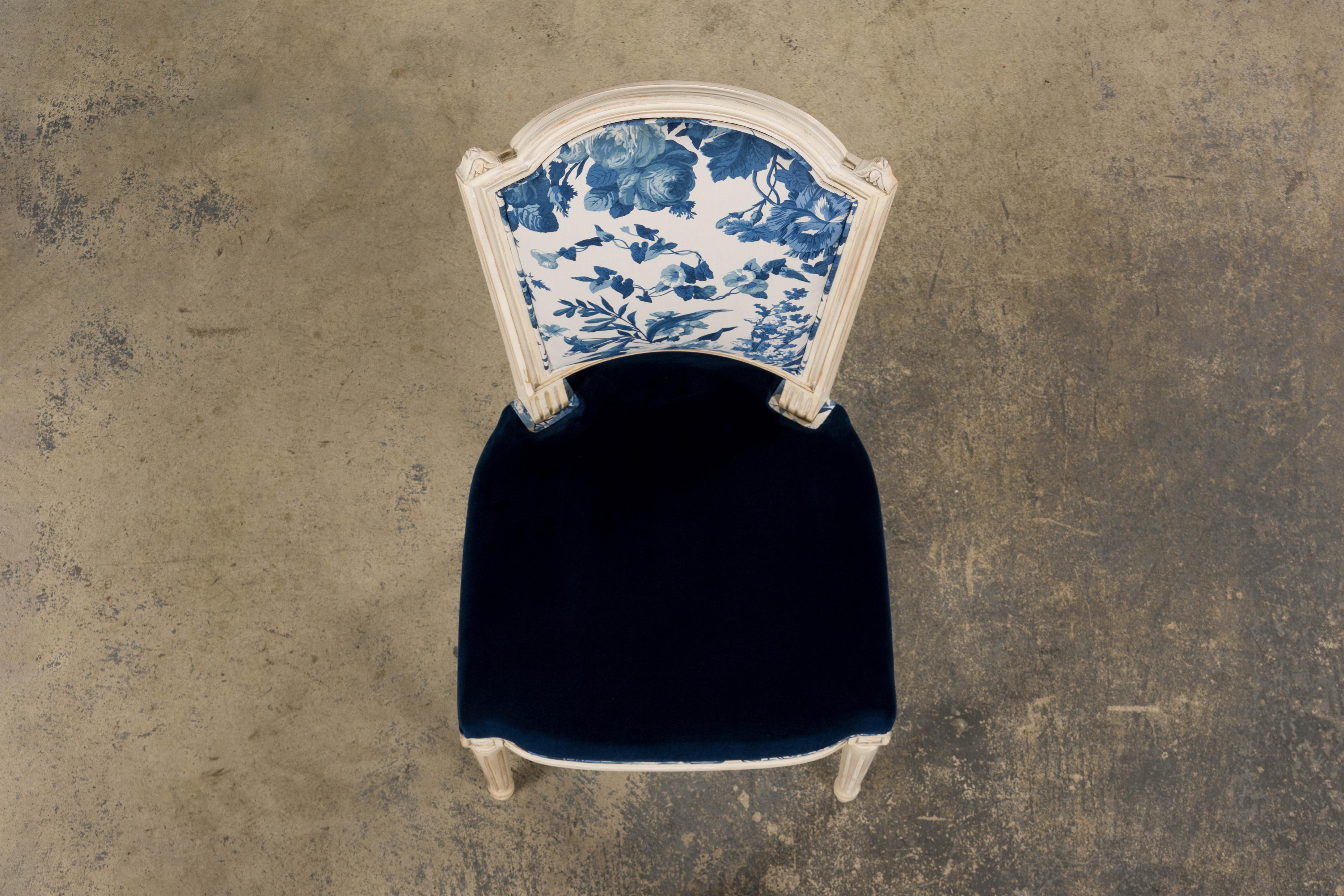 An exquisite restored antique French accent side chair in the Marie Antoinette/Louis XVI style, sourced from Provence, France. The chair features a finely hand-carved shield-shaped backrest, finished in a creamy antique white paint with a naturally