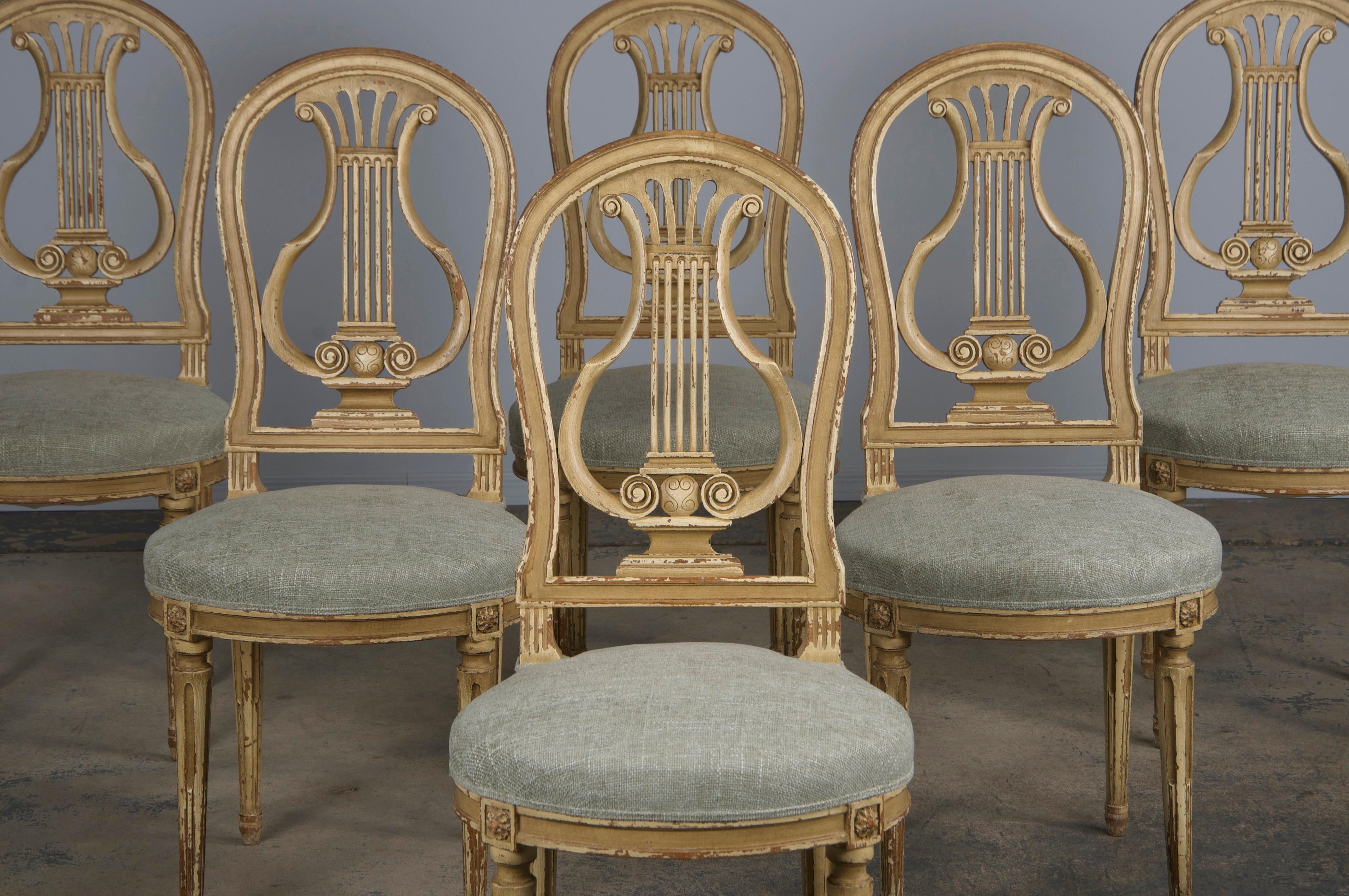 An elegant set of six late 19th-century French dining chairs in the Louis XVI Neoclassical style, sourced from Provence, France. Each chair features a handcrafted frame with an oval-shaped Neoclassical balloon lyre-back, beautifully hand-painted in