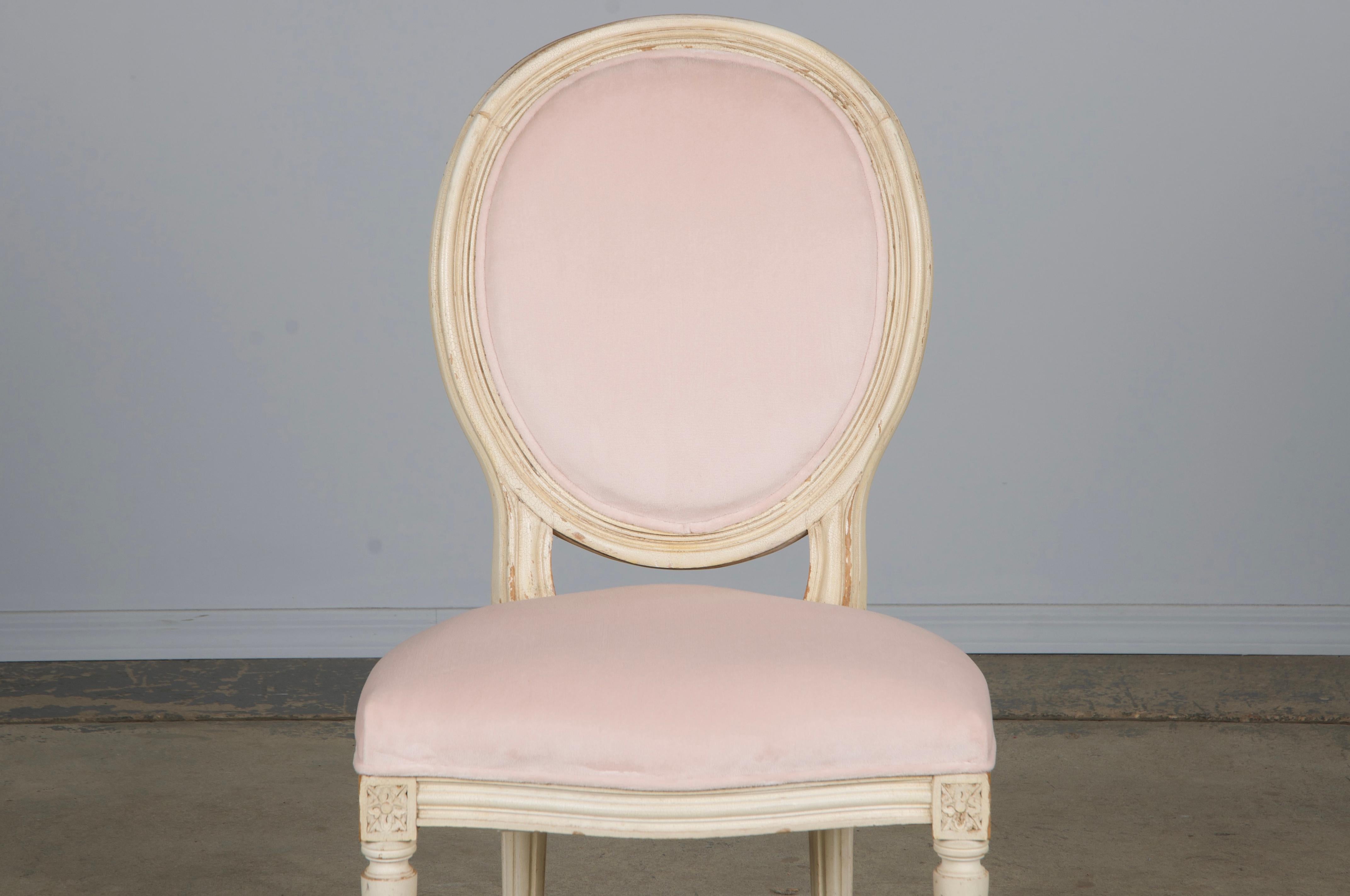 A lovely early 20th-century side chair in the style of Louis XVI, sourced from Provence, France. Handcrafted with an oval medallion back, the frame is painted in a creamy antique white with a naturally aged crackled patina and areas of characterful