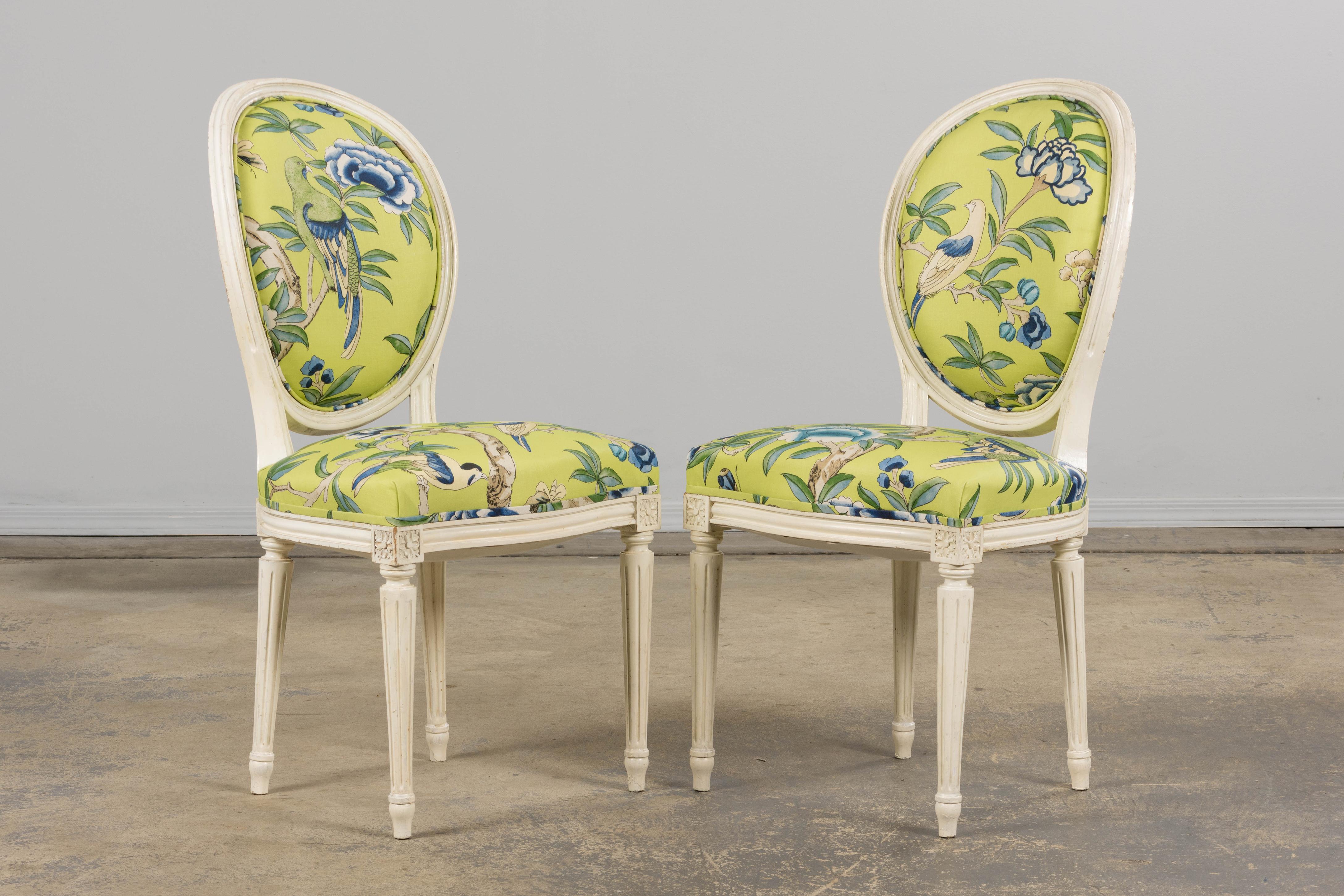 An exquisite pair of late 19th-century Louis XVI-style accent chairs, sourced in Provence and newly reupholstered in a richly expressive Chinoiserie-inspired cotton. The hand-carved frames feature oval backrests, fluted columns, rosette accents, and
