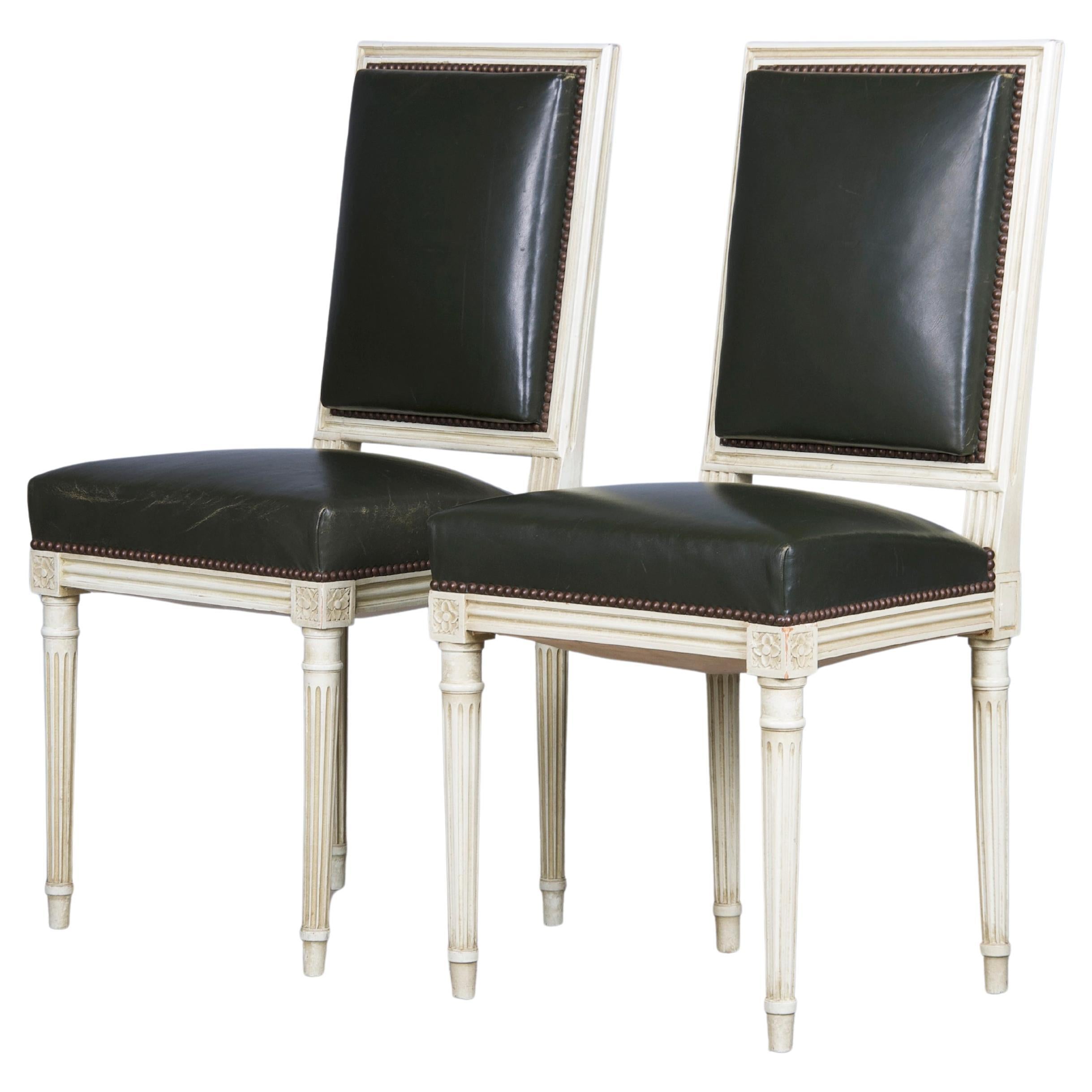 A magnificent pair of antique side chairs made in the style of Louis XVI, sourced from Provence, France. Each chair showcases a hand-crafted frame, featuring a square-shaped back hand-painted with a creamy white finish showcasing a naturally aged