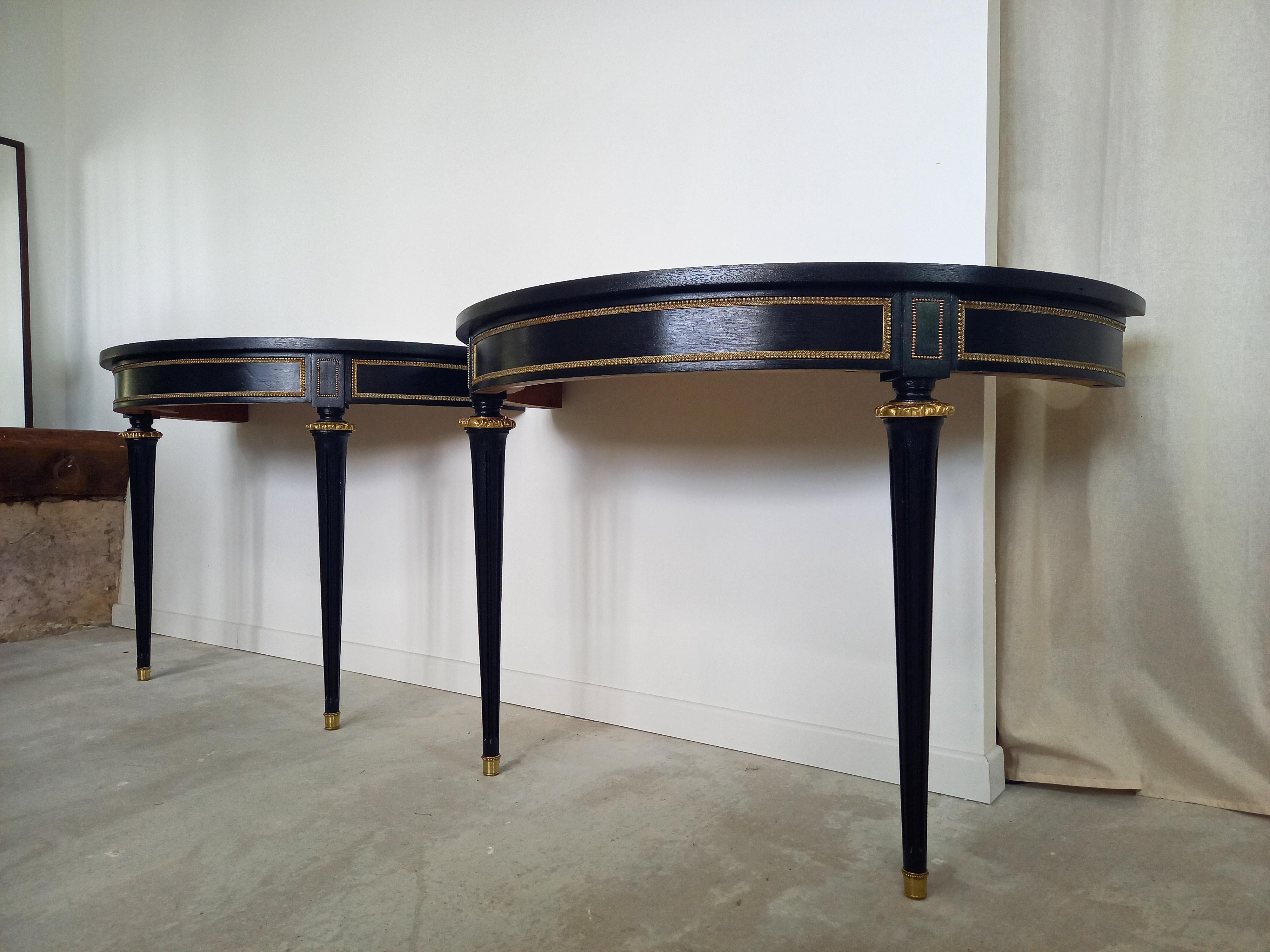 Antique Pair of Louis XVI style console, with cognac leather top and gold brass and bronze details. 
The feet are fluted and finished with golden bronze clogs.
To be placed against a wall (and fixed with a wall bracket from below), in an entrance,