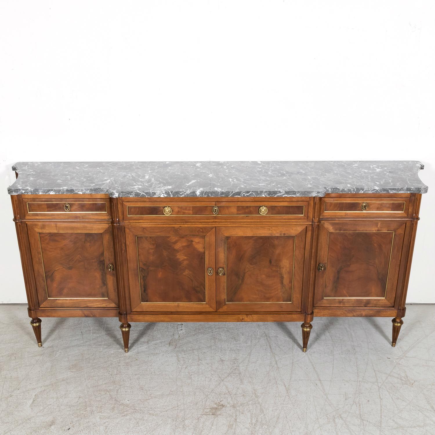 An exquisite antique French Louis XVI style enfilade buffet, handcrafted in Paris of walnut, circa 1920s, that embodies the timeless appeal and meticulous craftsmanship synonymous with Parisian ateliers and epitomizes the elegance and sophistication