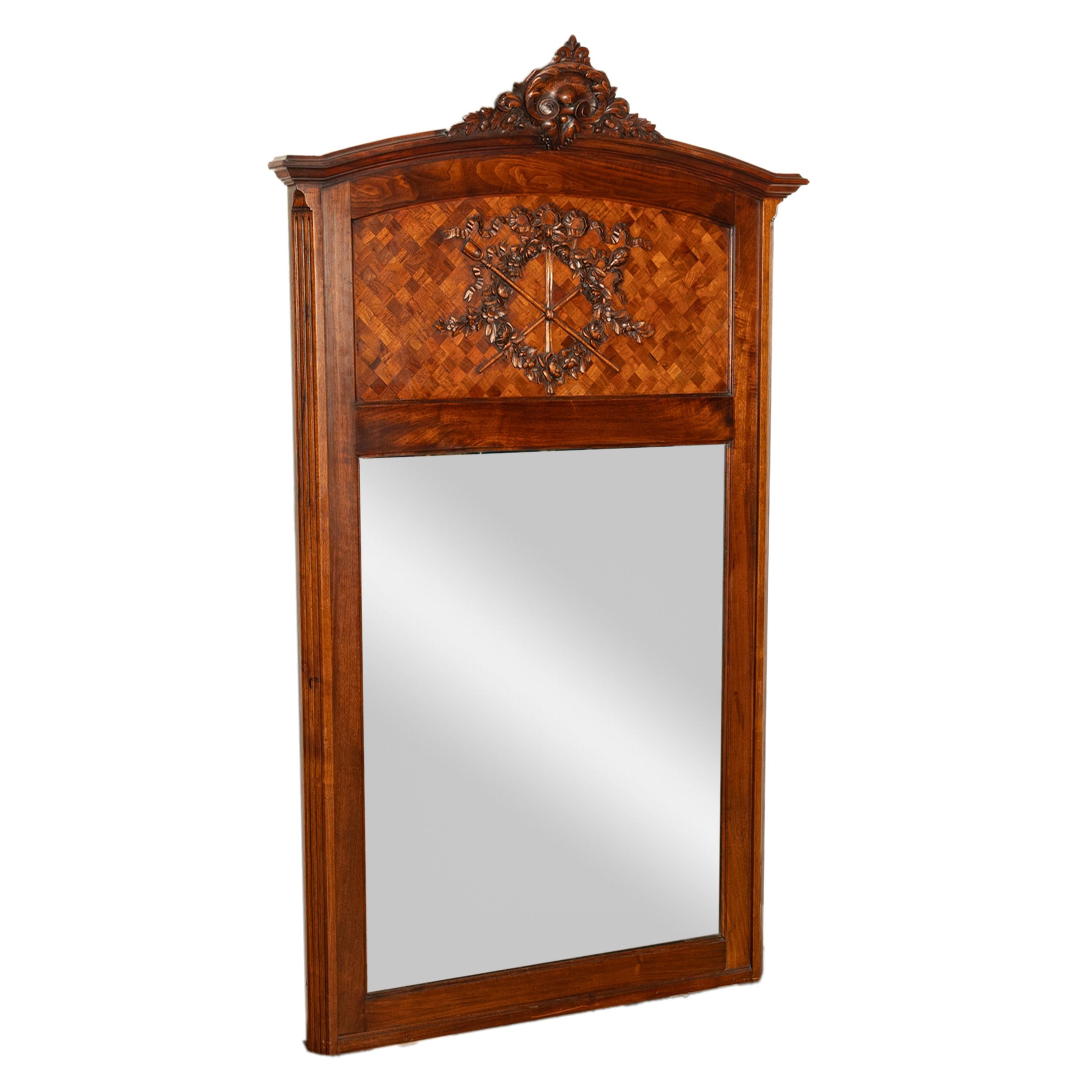 Antiker, eleganter französischer Spiegel mit geschnitztem und eingelegtem Parkett im Louis XVI-Stil, um 1890.
Der Spiegel hat eine gewölbte Oberseite mit einem geschnitzten Wappen auf der Oberseite mit einer Fleur des lis, Schriftrollen und