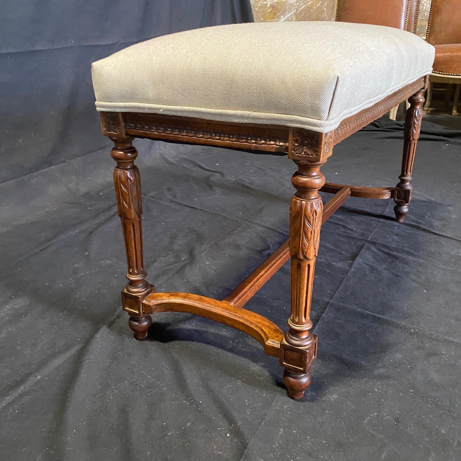 A beautiful and high quality French walnut Louis XVI bench raised by elegant fluted baluster shaped legs with exceptionally carved acanthus leaf designs and shaped foliate feet below fluted block reserves each connected by a most decorative curved