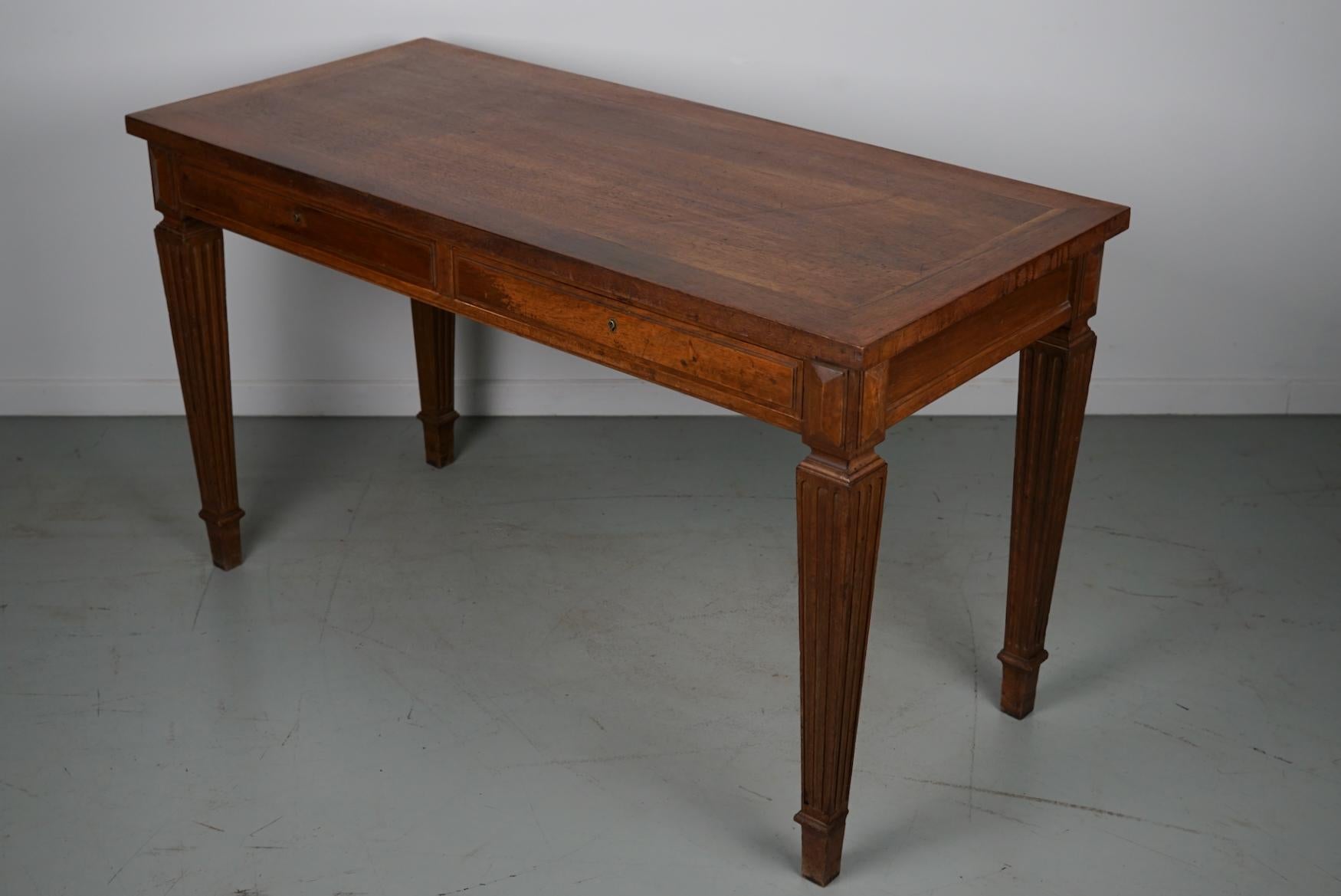 This writing table was designed and made in France from walnut wood around the 1920s. It features two drawers and has nice details on the legs.
