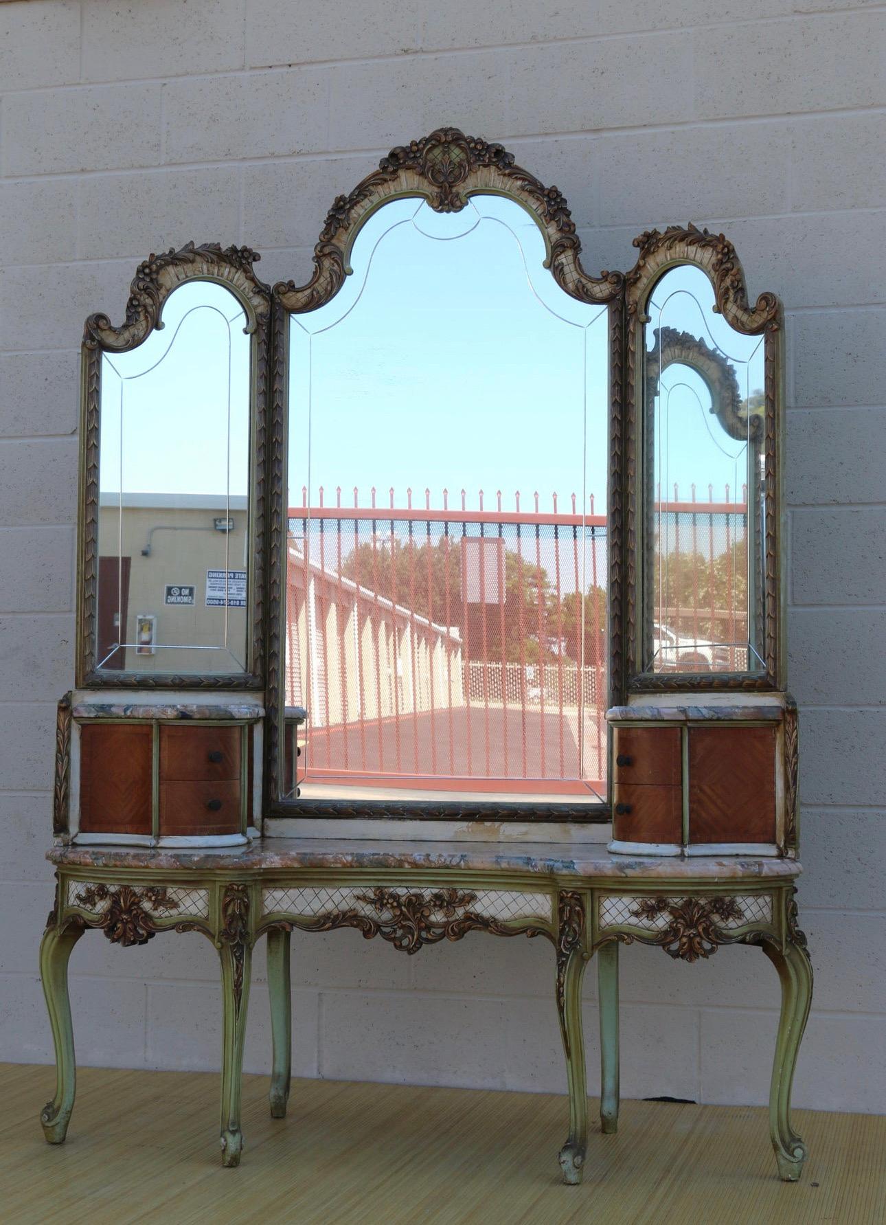 Spectaculaire meuble de toilette français ancien avec miroir à trois panneaux rabattables et deux armoires, deux tiroirs dans chacune d'elles. Il y a également trois plateaux en marbre qui se détachent. Cette coiffeuse date des années 1920.
