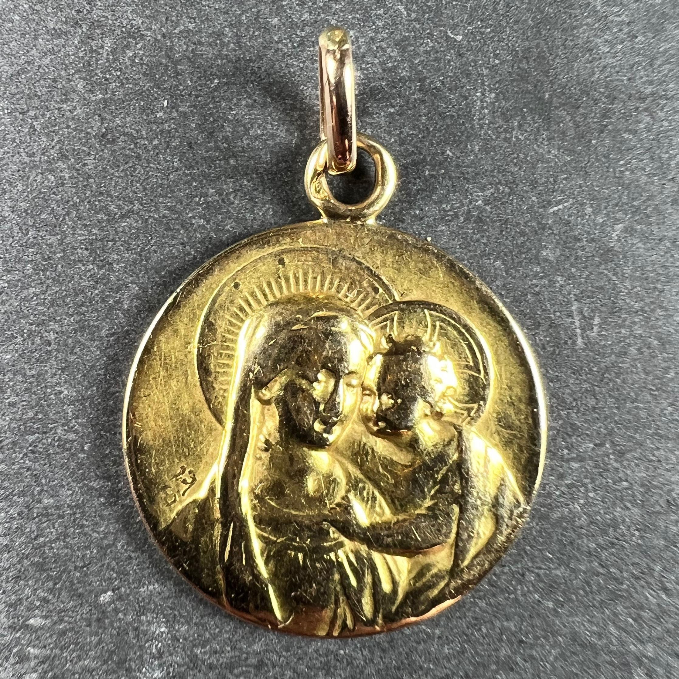 A French 18 karat (18K) yellow gold charm pendant designed as a medal depicting the Madonna and Child. Stamped with the eagle’s head mark for 18 karat gold and French manufacture. Engraved to the reverse with the monogram EJ and the date 8th August