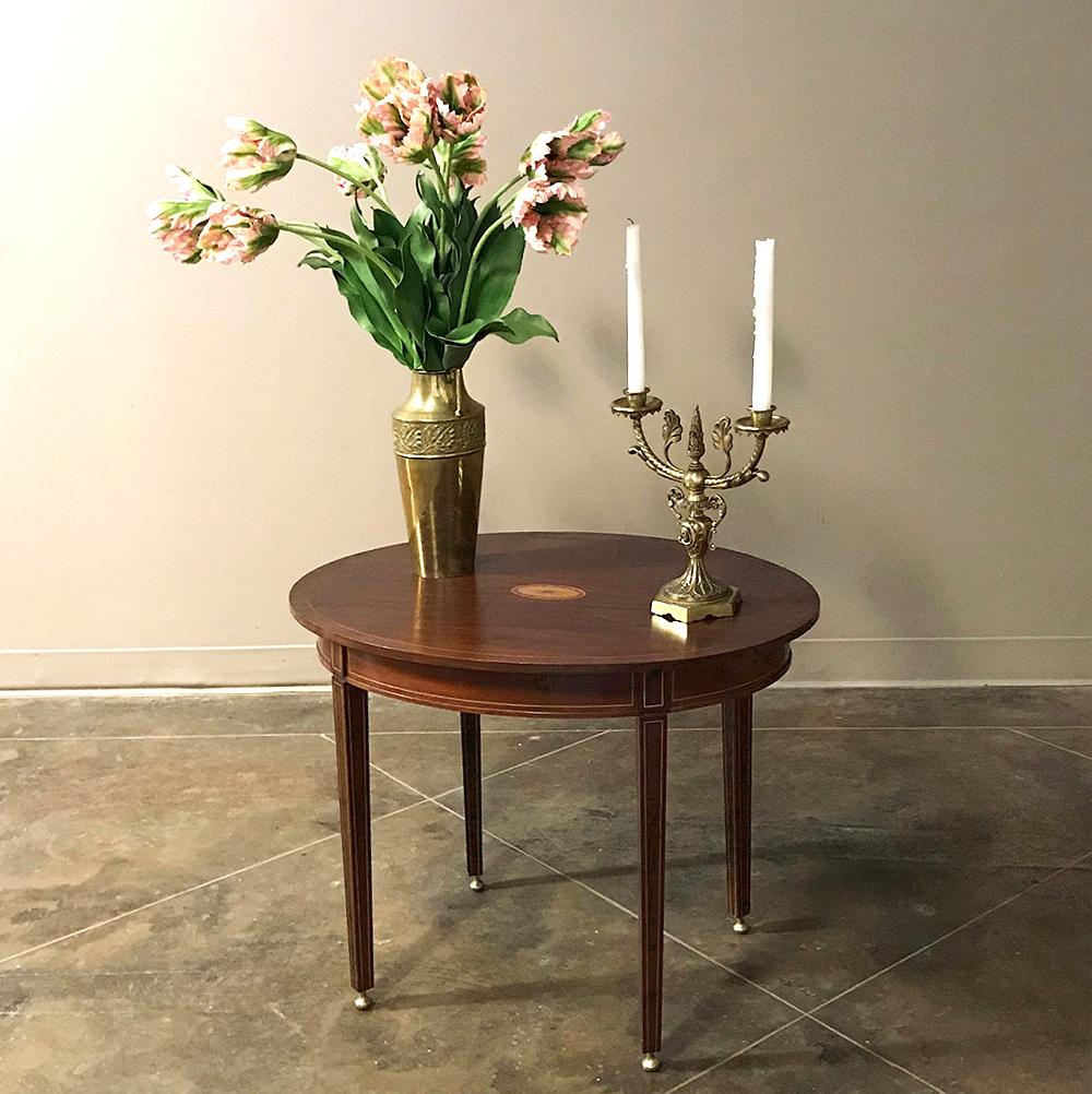 Antique French mahogany Directoire inlaid end table features the tailored lines that make this style so popular for any decor! Inlaid French borders on the tapered legs complements the inlaid circular fan motif, or marquetry, centered on the oval