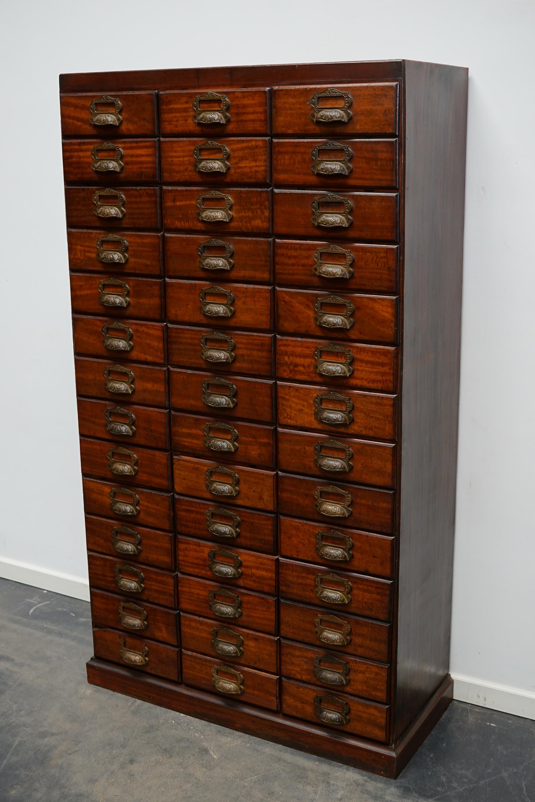 This unique filing cabinet / bank of drawers was designed and made around the turn of the century in France. The piece is made from mahogany with bronze hardware. The interior dimensions of the drawers are: D 30 x W 26 x H 7.5 cm.