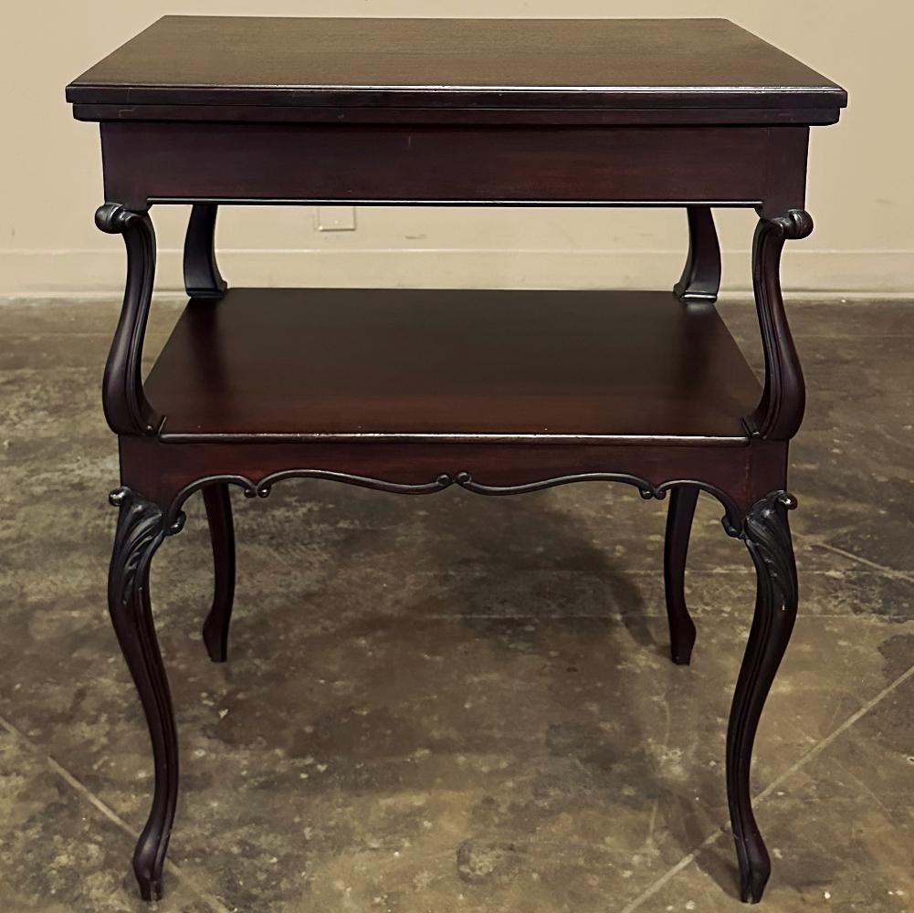 Antique French mahogany flip-top game table was sculpted from exotic imported mahogany in the timeless Louis XV manner, with two tiers supported by four scrolled and carved legs. The lower tier acts as a convenient shelf while providing structural
