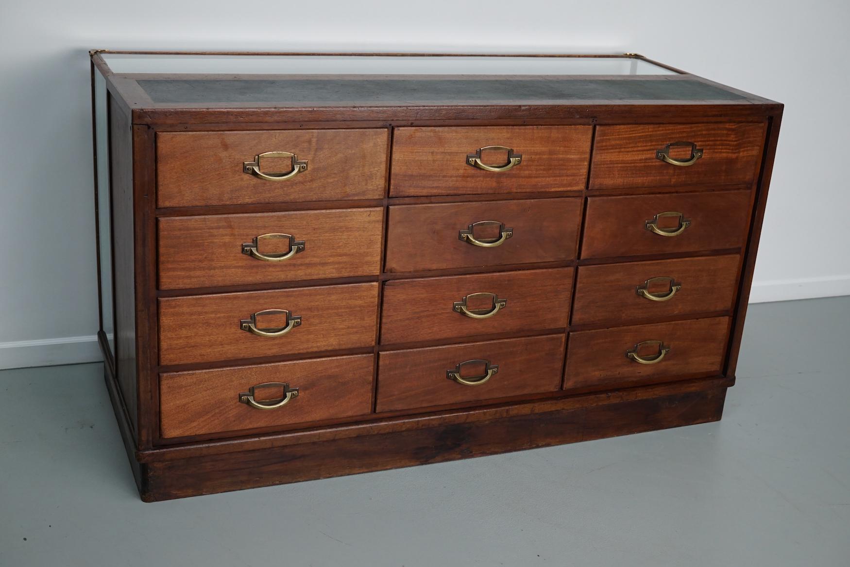 This mahogany haberdashery shop counter dates to the 1920/30s and was made in France. It features a mahogany frame, glass casing, linoleum inlay and stunning brass handles.