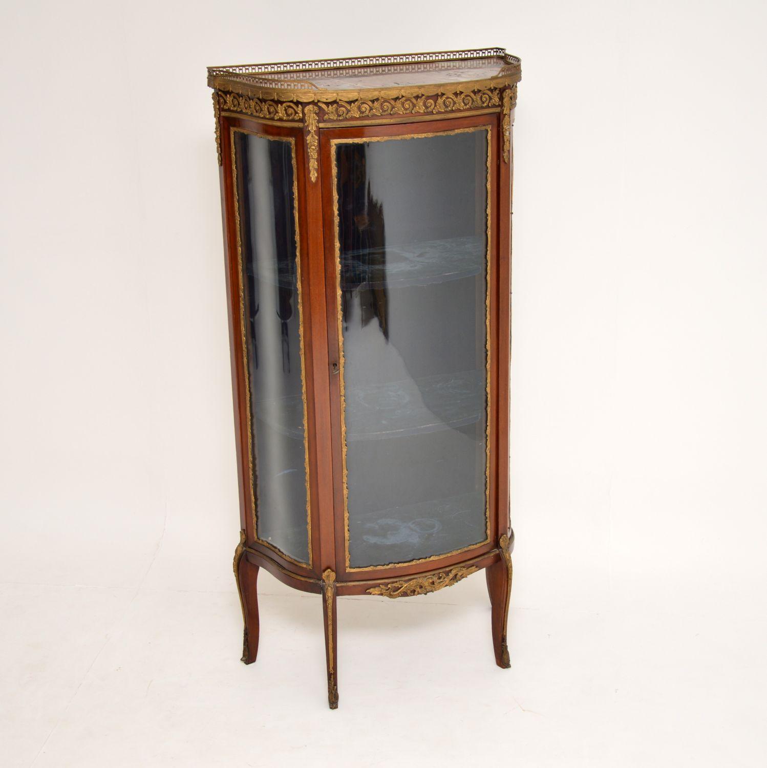 French antique Louis XV style mahogany display cabinet dating from circa 1880s-1890s period and in very good original condition.

It has a marble top with a gilt metal pierced gallery with swags below. There are gilt bronze mounts on the top, on