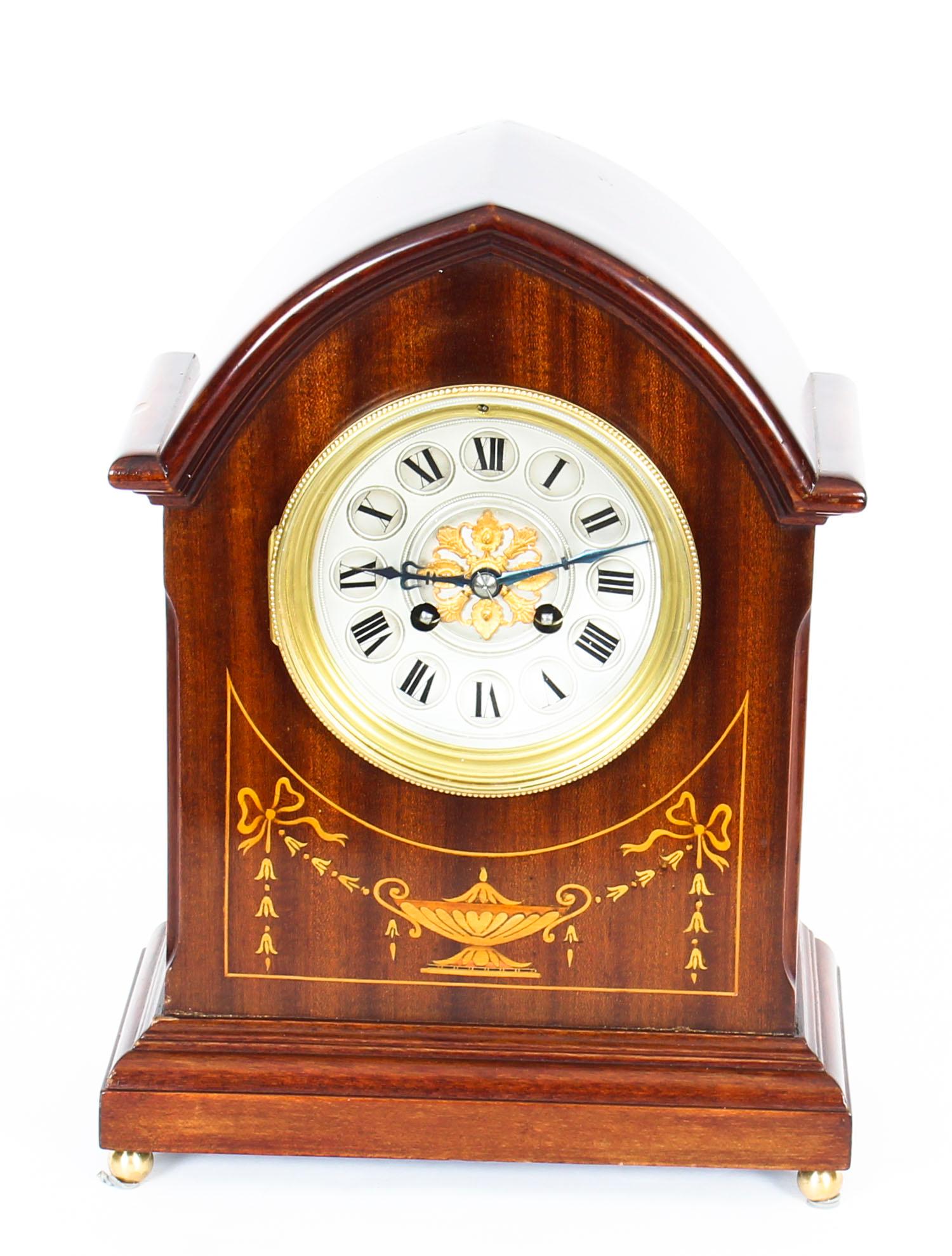 A delightful French Marquetry inlaid mahogany lancet-top mantel clock, circa 1900 in date.

With brass and silvered concave dial, Roman chapter ring and gilt rosette center fronting an eight-day spring driven French movement with gong