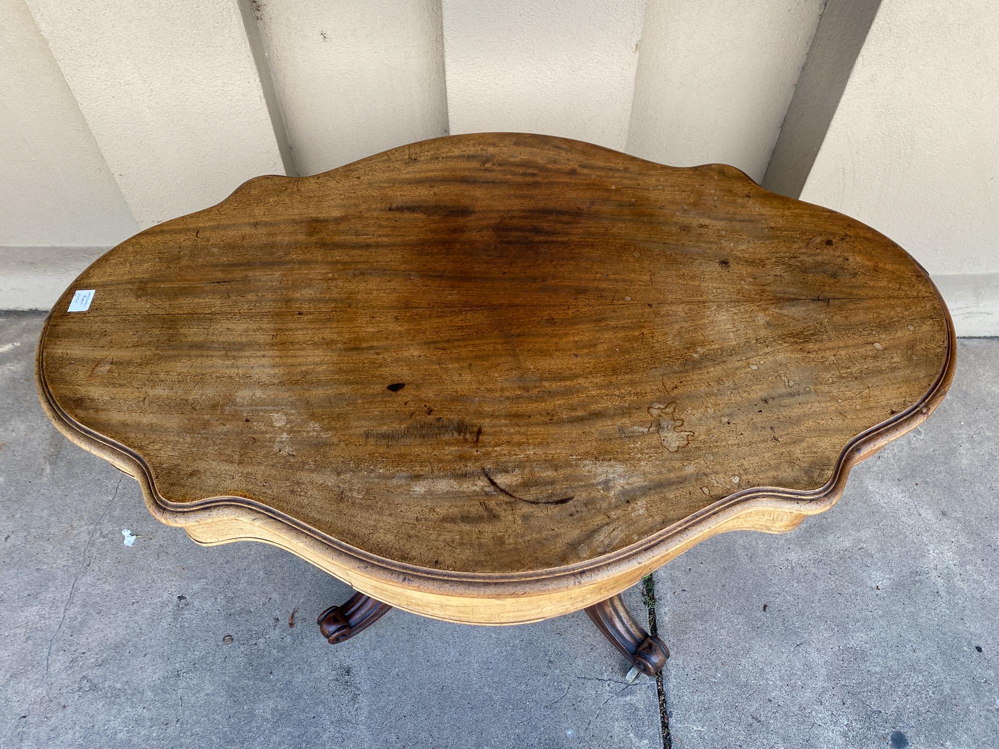 Questo tavolino francese antico è realizzato con un piano dalla forma unica e una base a piedistallo. La base è dotata di gambe cabriole su rotelle ed è facilmente spostabile. Ogni lato del tavolo ha un cassetto al centro che è accuratamente