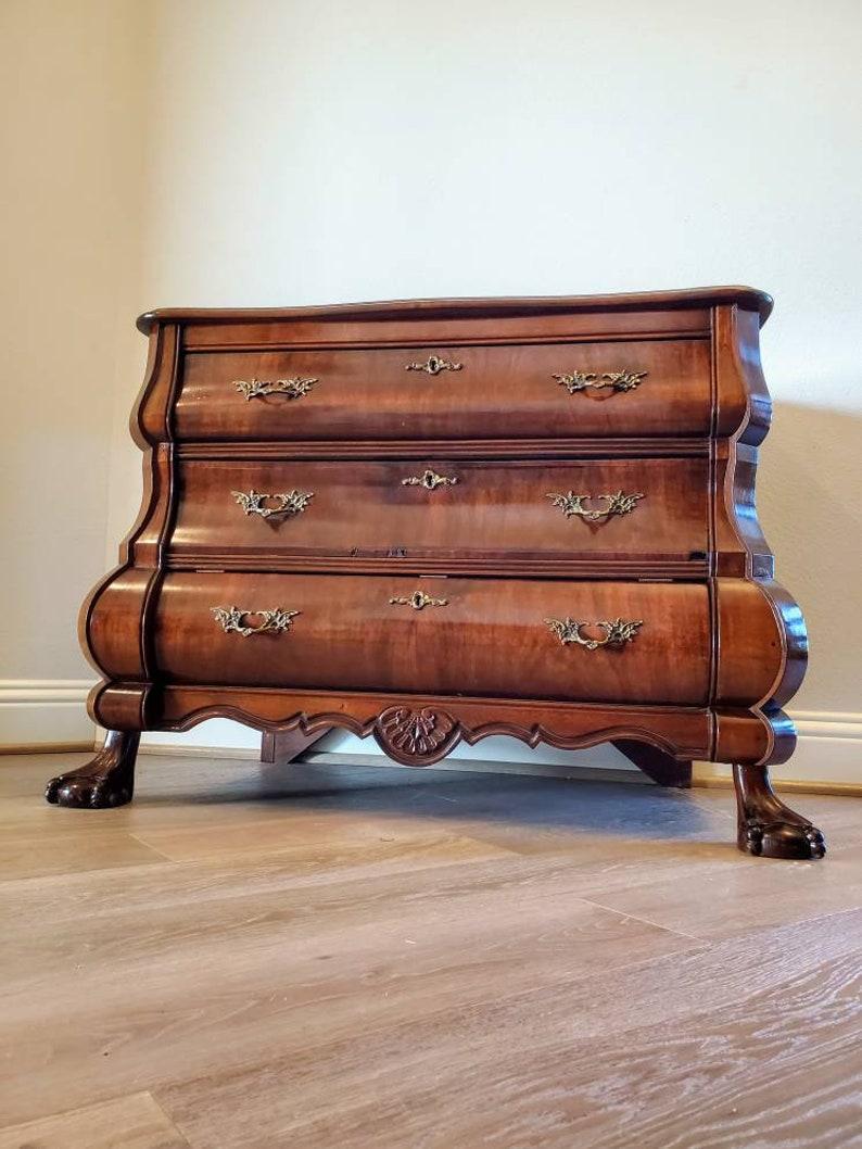 A stunning antique Dutch mahogany and burled walnut bombe chest of drawers petite commode low boy from the early 20th century. 

Hand-crafted fine quality craftsmanship, detailing, and solid wood construction, having a beautiful book-matched