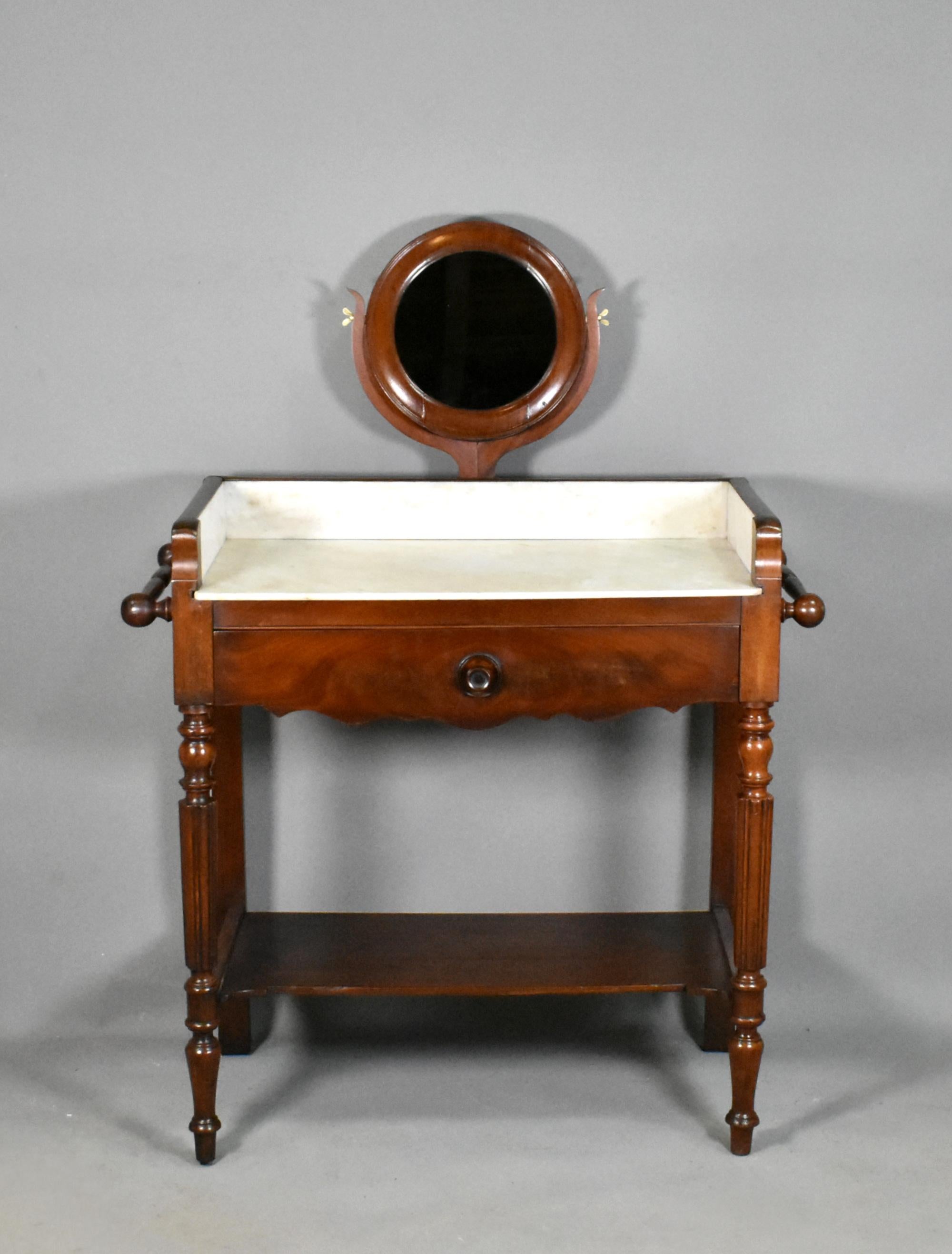 Antique French Mahogany Washstand Louis Philippe Style 

A delightful mahogany washstand featuring a variegated white and grey marble top and surround to three sides. 

A round central pivoting mirror stands on the top within a lyle frame.