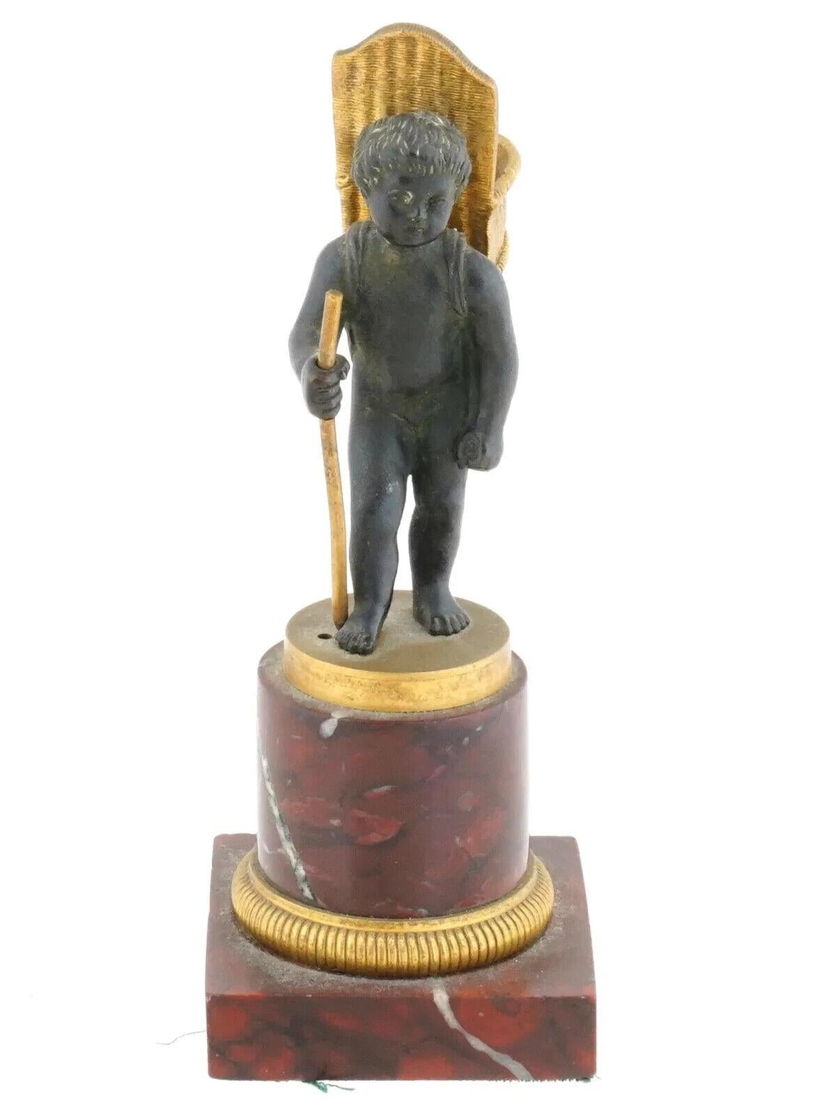 An antique French manner patinated bronze sculptural match holder. The ware represents a child carrying an open basket and holding a stick. Mounted on marble base and stand. Unmarked. Circa: late 19th century to early 20th century. Antique European