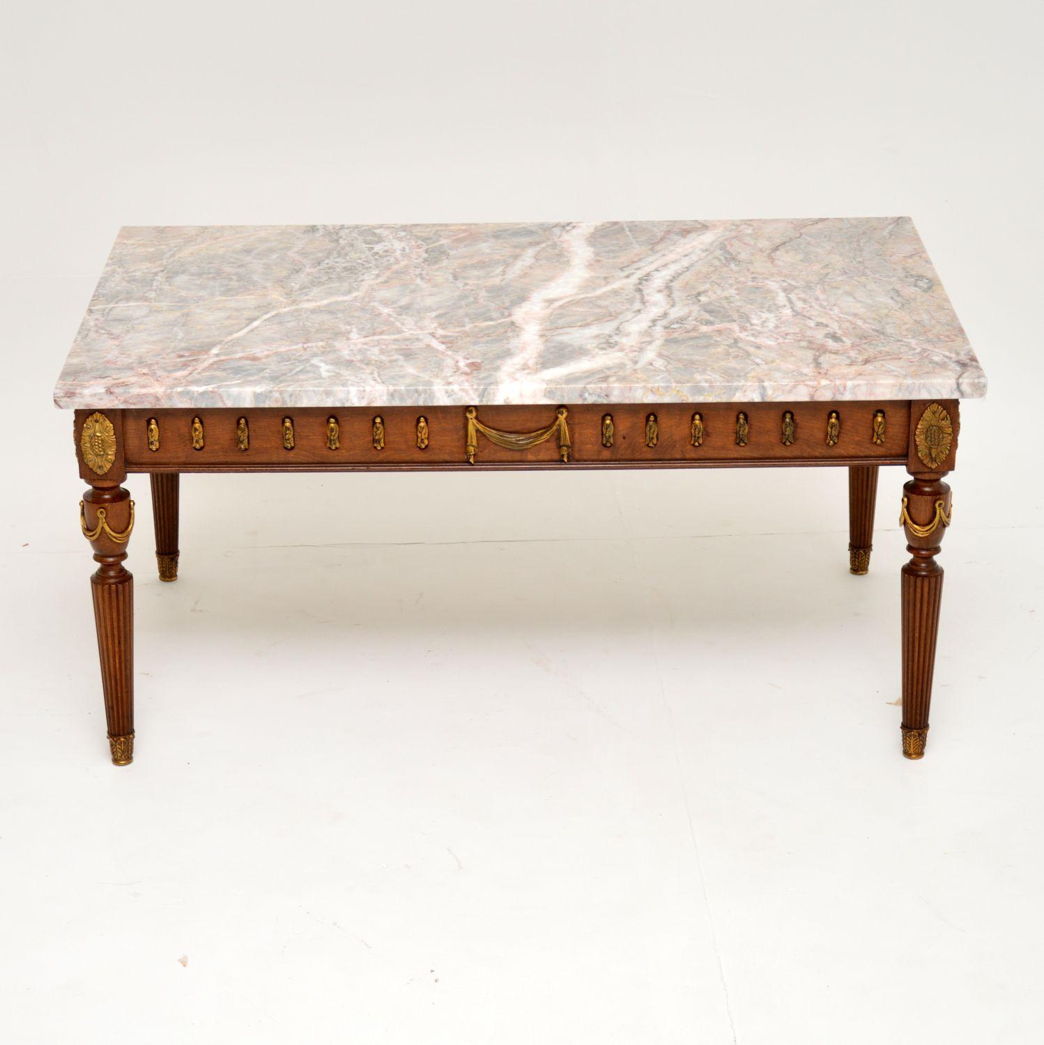 Antique French style marble top mahogany coffee table, in very good condition and dating to circa 1950s period.

The marble top has some beautiful colored veins and just lifts off from the base. The base section has many gilt bronze mounts, swags