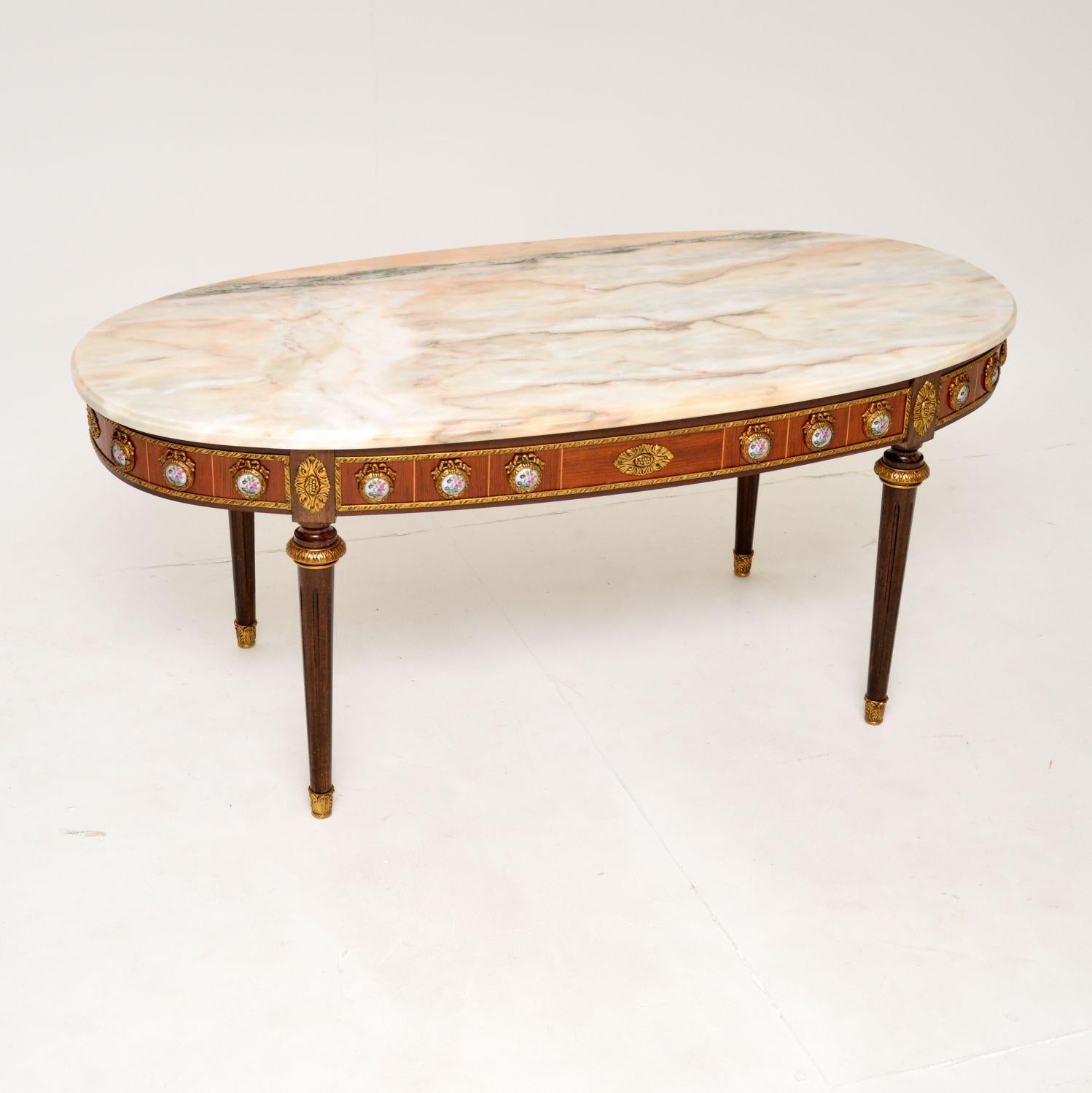 A beautiful antique French marble top coffee table, dating from around the 1930-1950’s.

It has a gorgeous design, with a mahogany and walnut frame, and stunning painted porcelain Limoges plaques set in gilt bronze mounts all around the top edge.