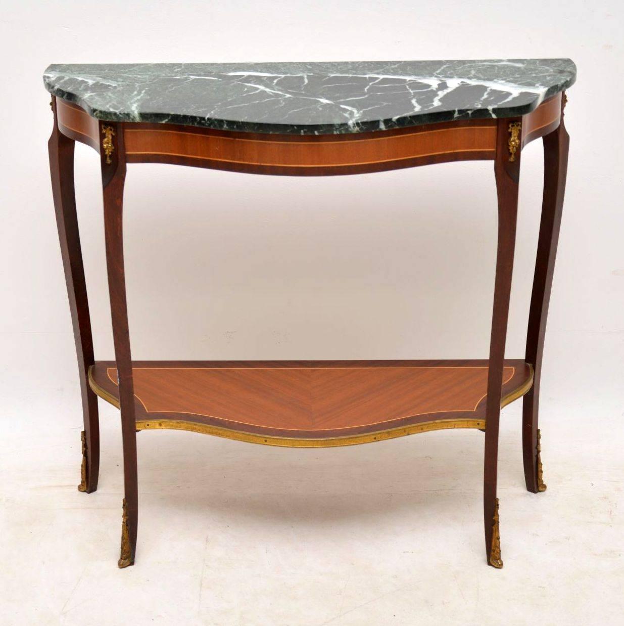 Antique French style marble-top console table in great condition, dating from around the 1930s-1950s period. The wood is kingwood and mahogany and it has gilt metal mounts. This table has a serpentine shaped front and the bottom tier also has a gilt