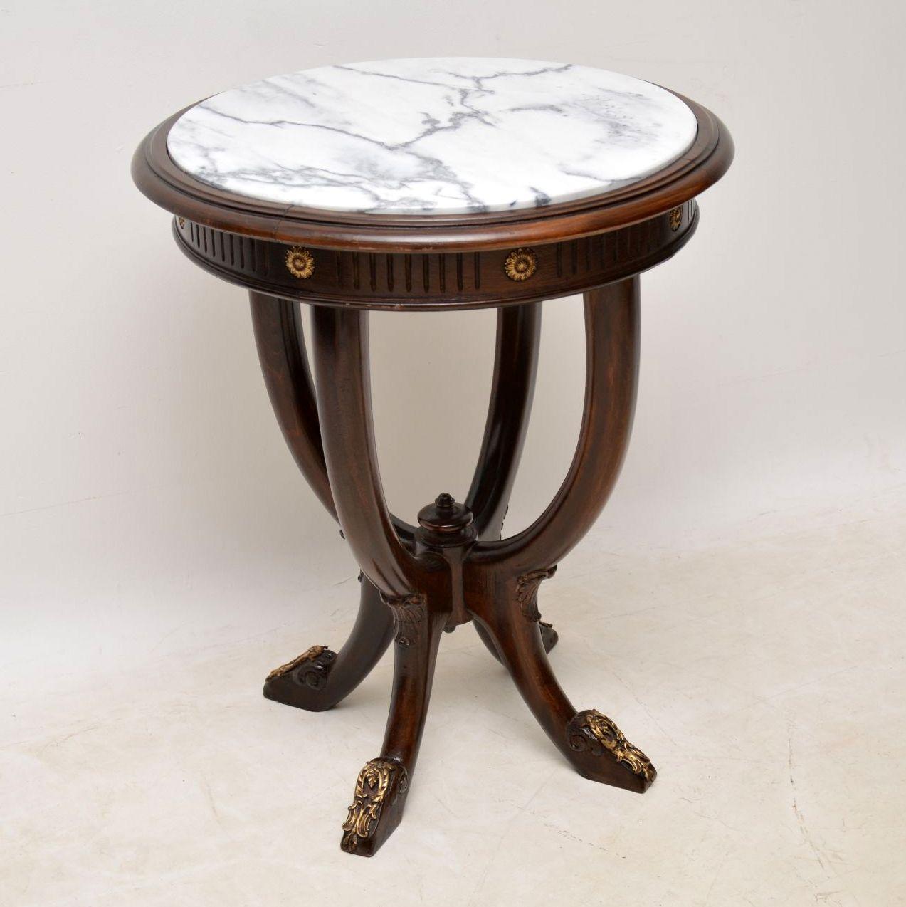 Antique marble top occasional table with original gilt metal mounts. The circular top has an inset marble and grooves around the edge, below which are four curved legs sweeping in and out. This is a very sturdy piece of furniture and is quite