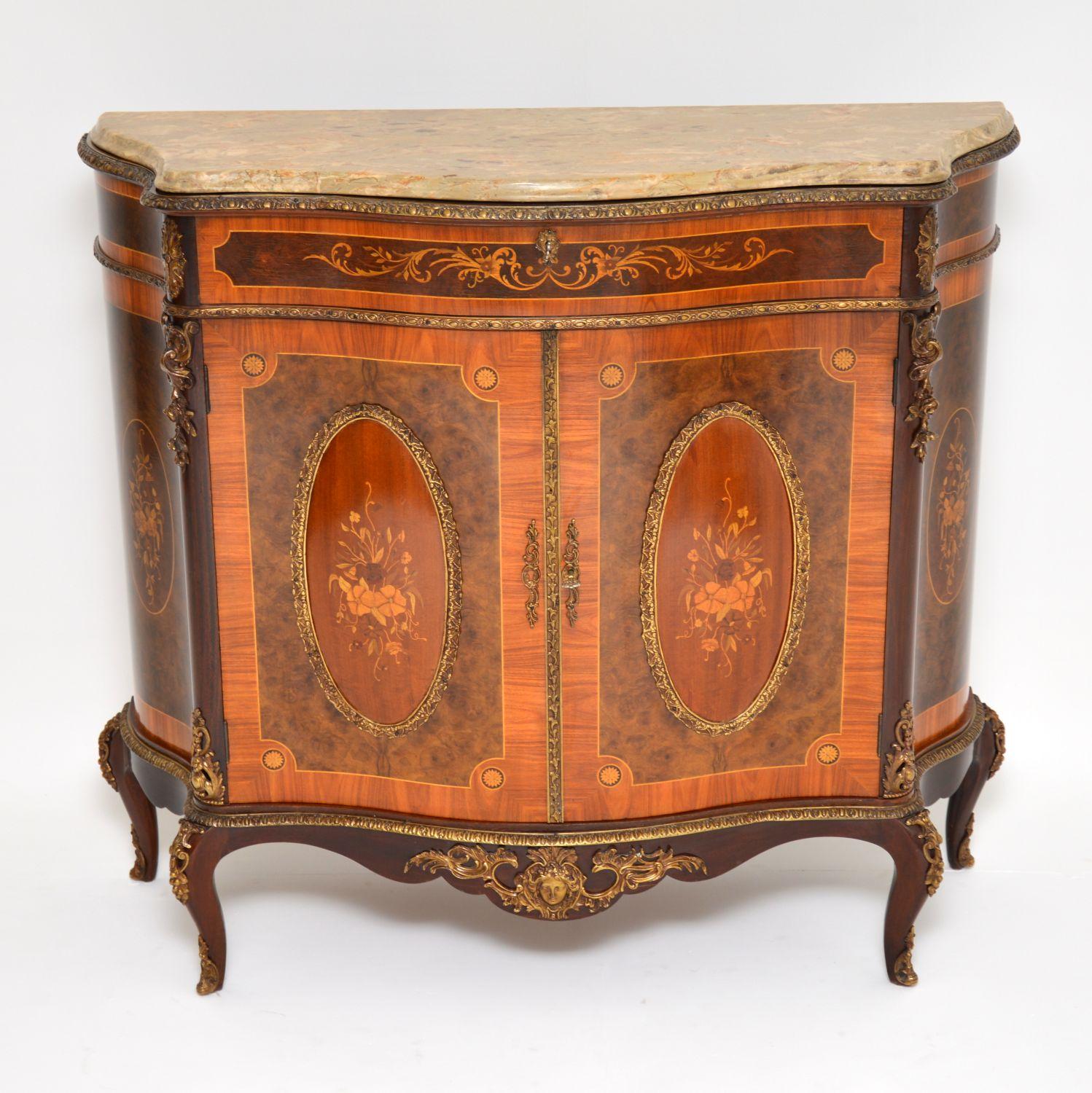 Fabulous quality and stunning looking serpentine shaped ormolu mounted cabinet, with a marble top and loads of marquetry.

There are many different woods involved, especially within the floral marquetry. The main woods are Kingwood, mahogany,