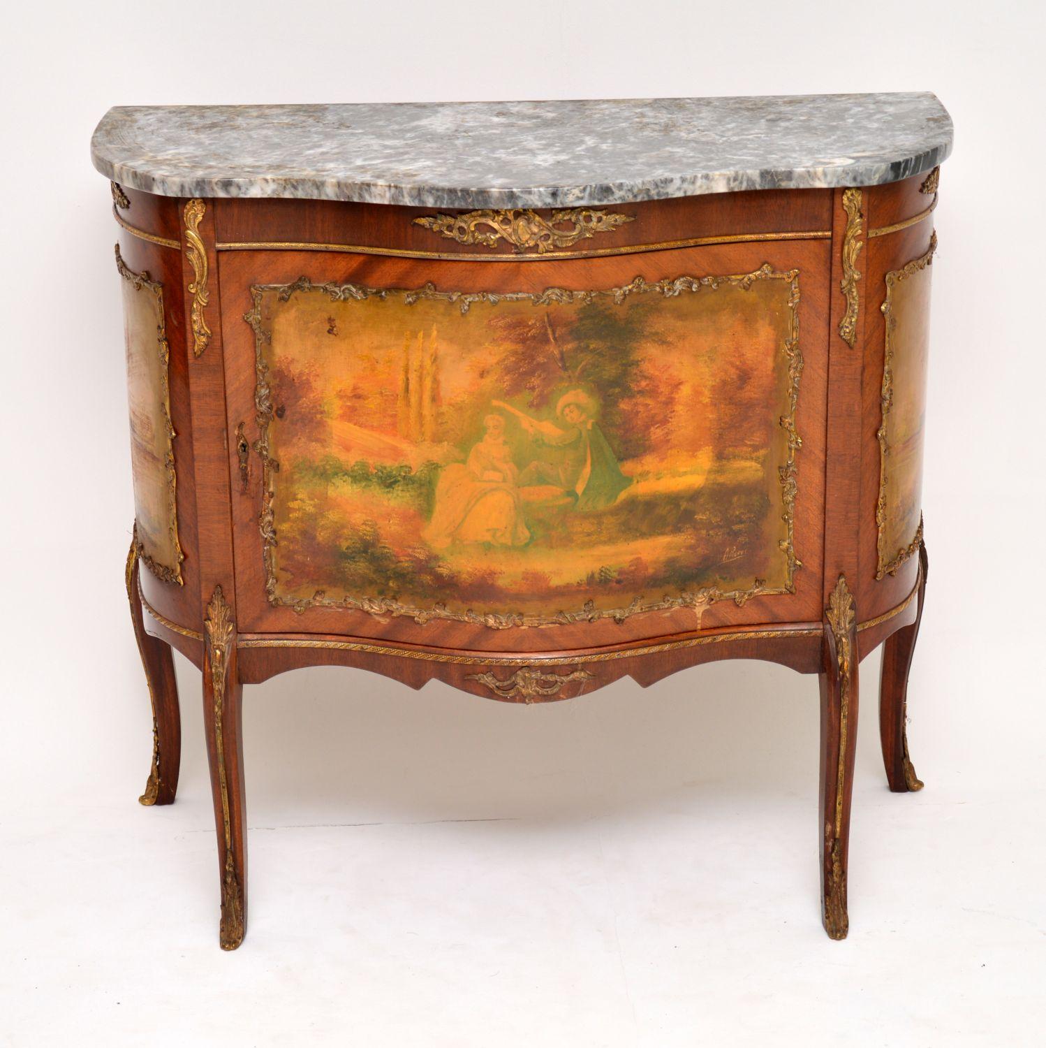 Antique French serpentine fronted marble top cabinet with decorative scenes on all three panels and in good original condition. It’s mahogany with the original marble top and gilt bronze mounts all over, which are well cast. There is plenty of