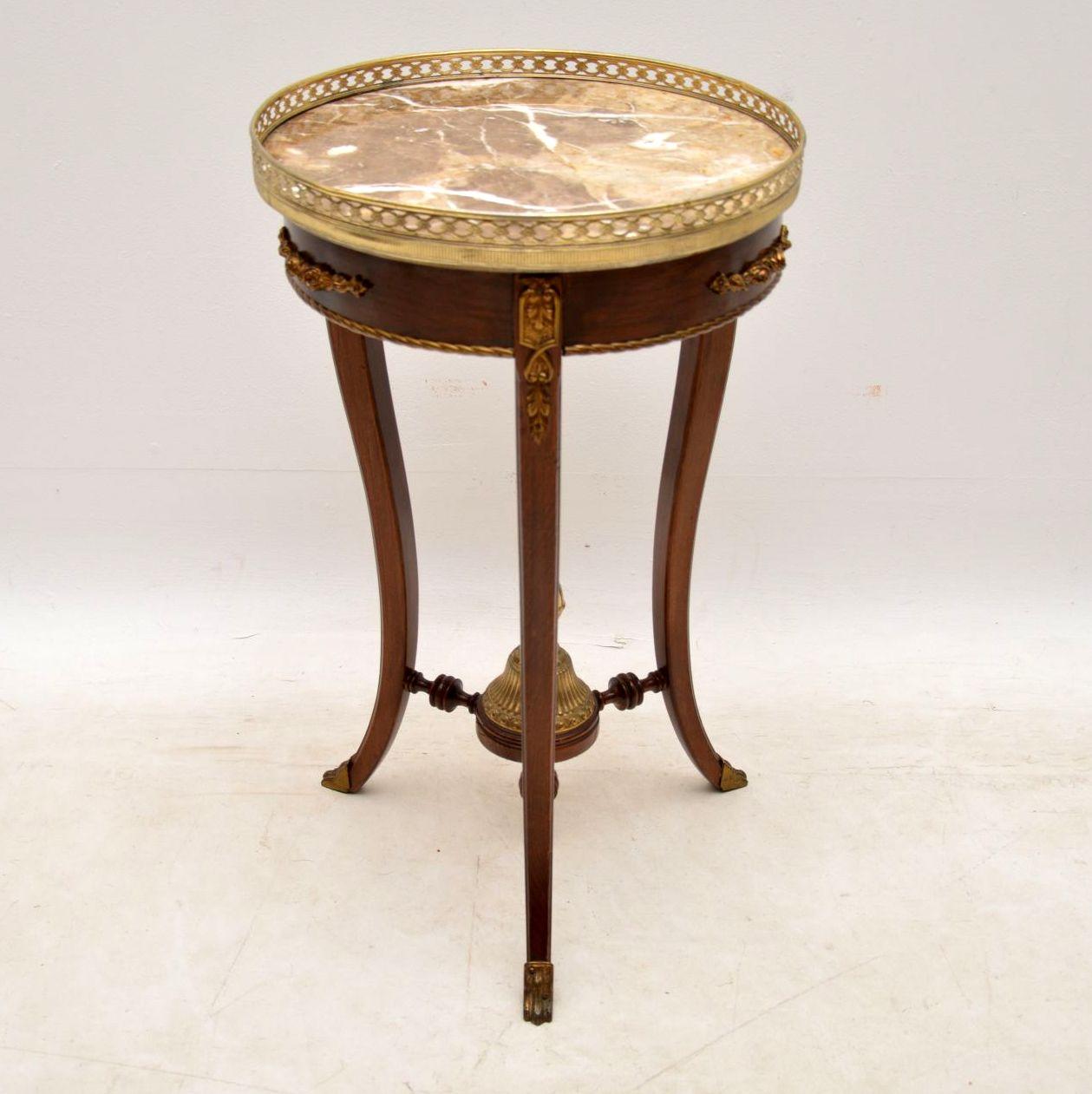 Antique French style marble-top occasional table with gilt metal mounts and a pieced gilt gallery around the marble top. There are three shaped legs with gilt metal feet. They are joined by three turned stretchers with a large gilt finial in the
