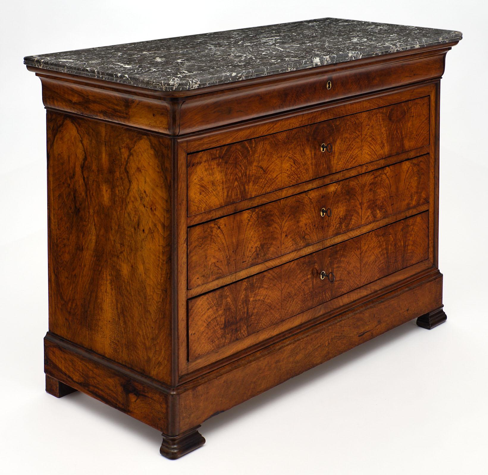 Louis Philippe antique French chest with marble top and four dovetailed drawers. This piece is made of solid walnut with veneered figured walnut on the facade. It is finished with a light French polish and waxed. We loved the intact Saint Anne