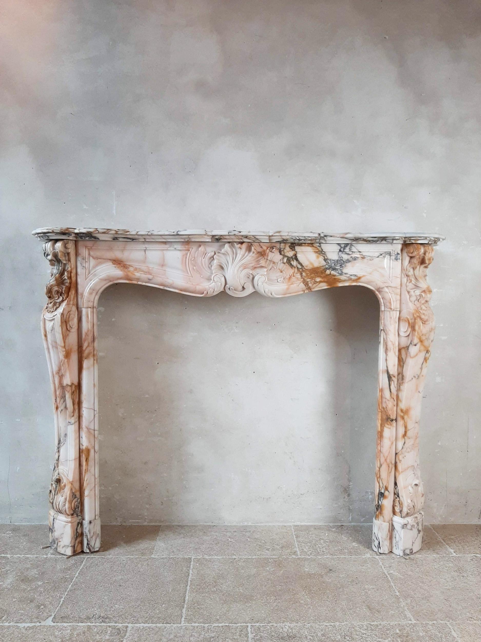 Antique French marble Trois coquilles fireplace in Louis XV style. The marble in a beautiful soft pink shade, with gray and cognac-colored nuances. Richly carved 19th century fireplace decorated with 3 scallops and acanthus leaf.

Dimensions: H