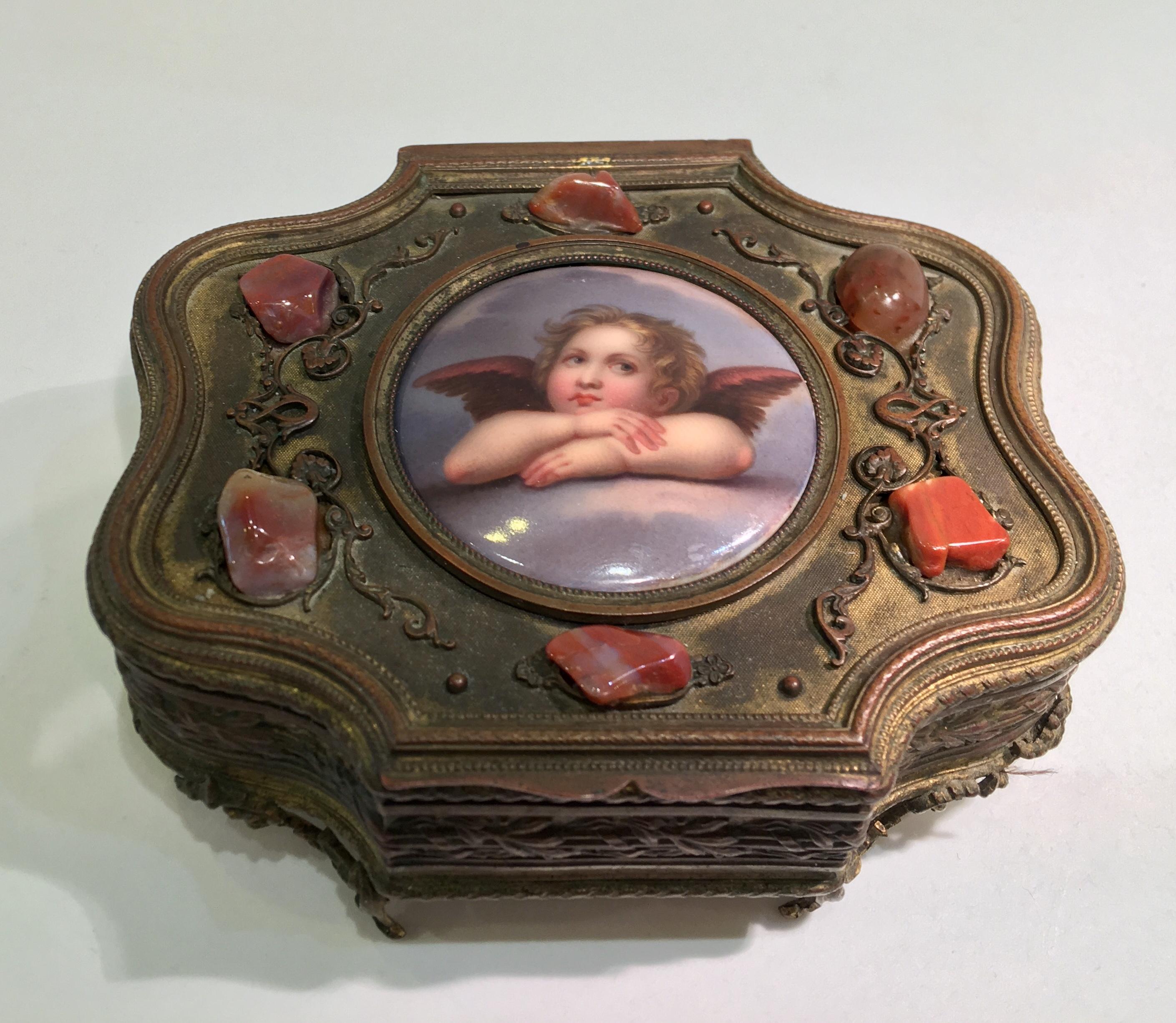 Beautiful antique, handcrafted French bronze and brass scalloped hinged jewelry or trinket or vanity box from the 19th century features a round porcelain plaque or disc, bezel set in the lid, exquisitely hand painted with a famous image depicting