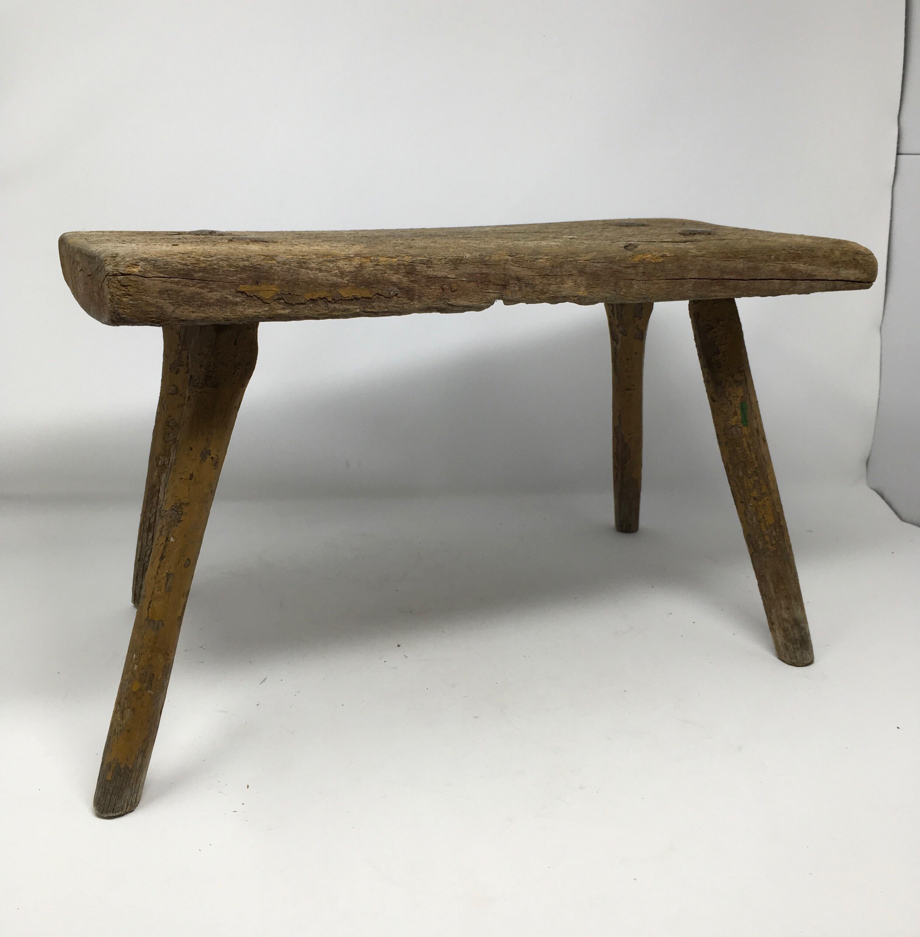 Found in the South of France, this antique French milking stool with aged patina and traces of original paint is made of solid hardwood and set on four hand hewn spindled legs. With its rustic charm, these types of milking stools can serve as a