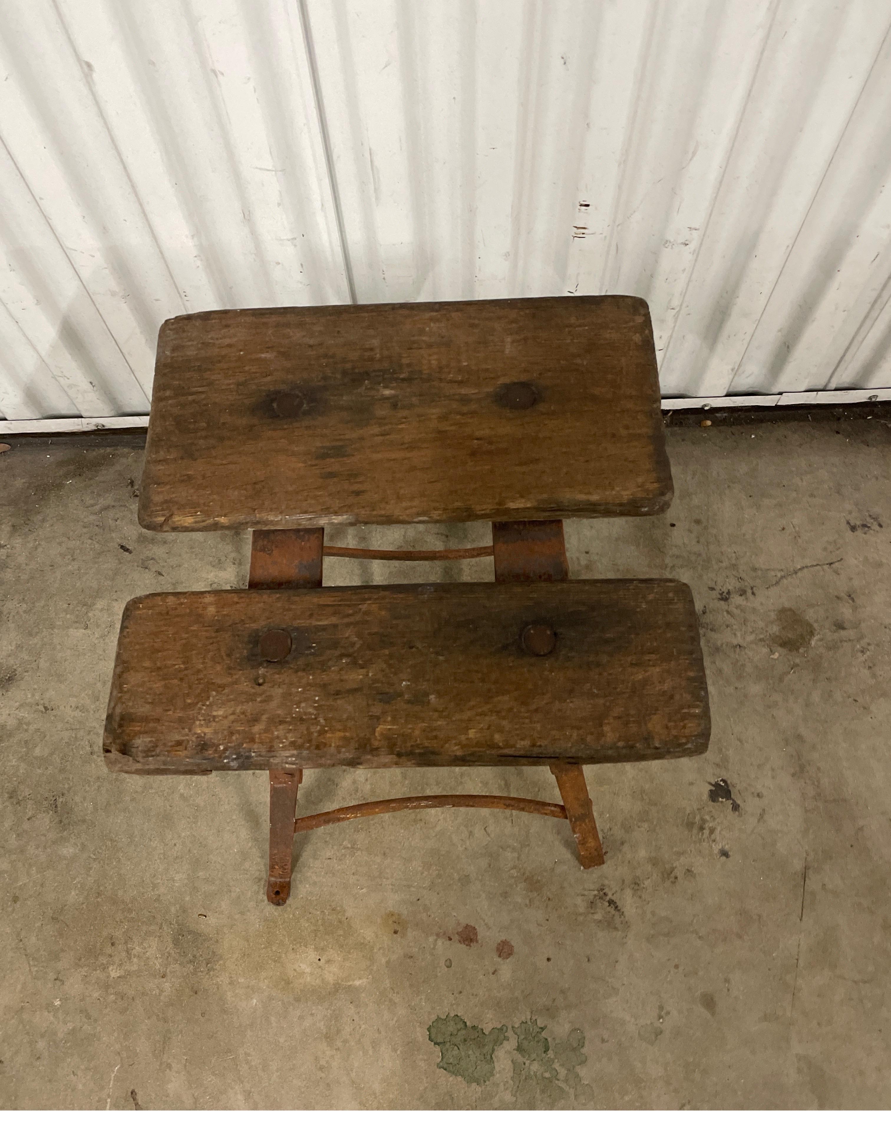 Antique French milking stool comprised of two wood slats on an iron base.
