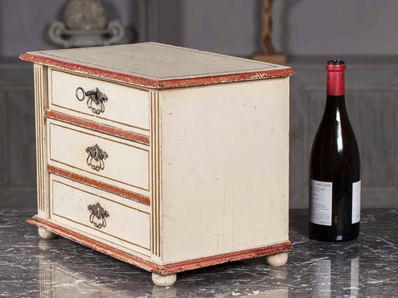 This charming example of an antique French miniature chest of drawers circa 1890 was used as a sample from which to order a full size chest for one's home. Fitted with three drawers, a working lock, elevated on bun feet and featuring a charming