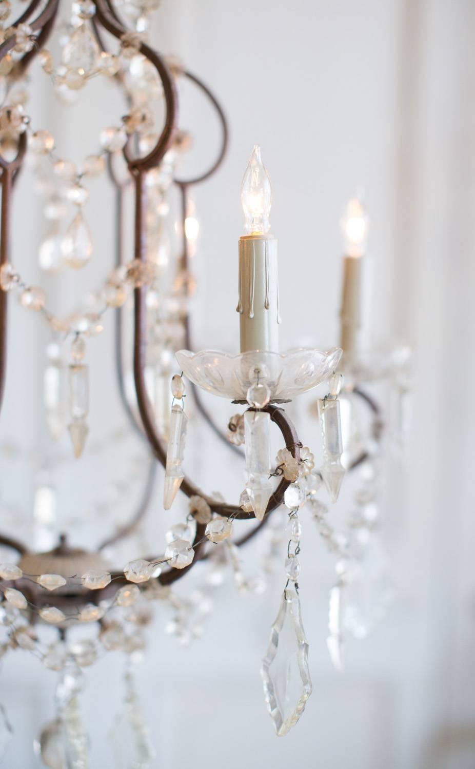 Petite chandelier with curved iron frame. Beautiful crystals drip between the wire arms and lend a delicate glow to a small room.