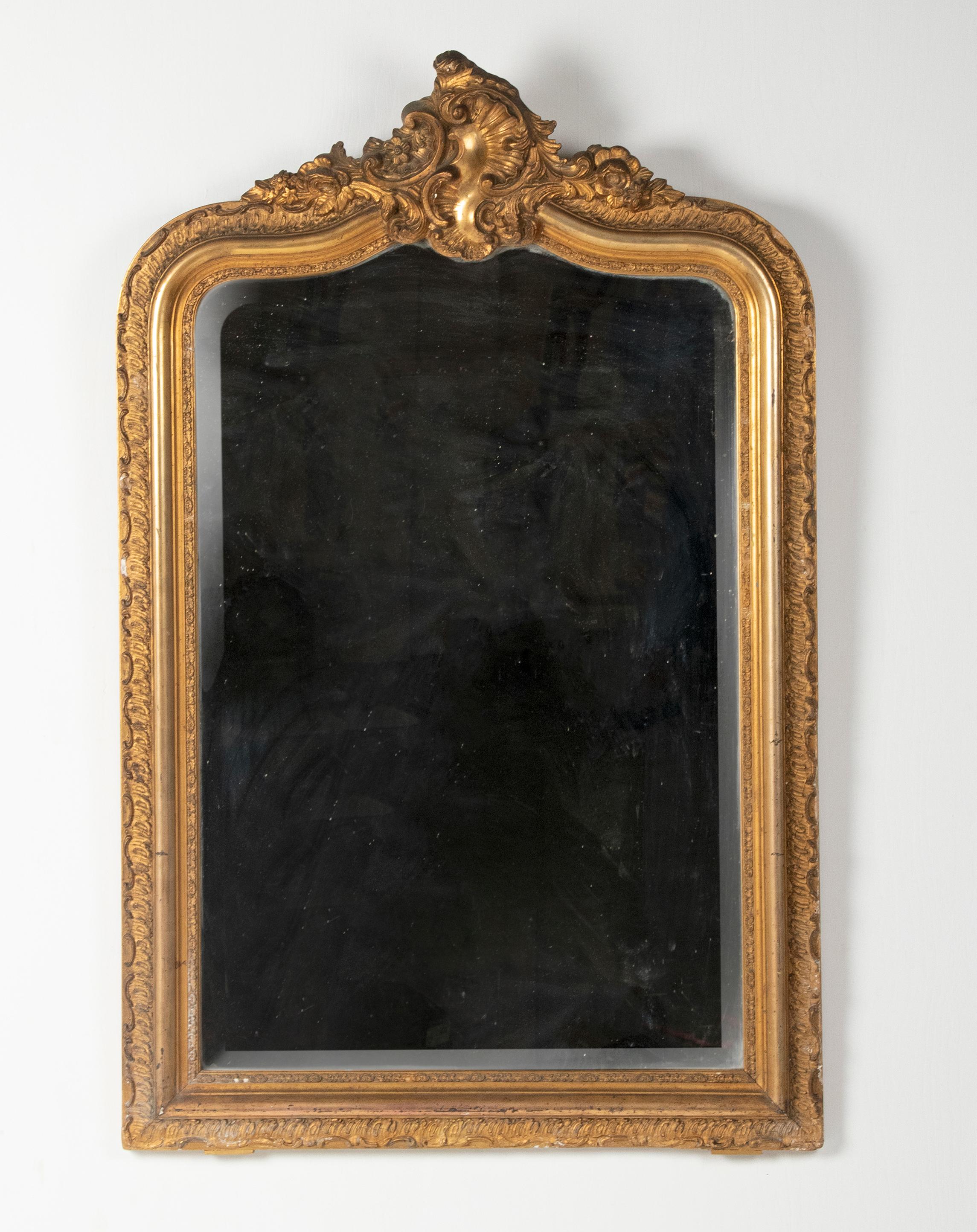 Beautiful antique French mirror. The mirror is made of wood, decorated with stucco and partly (the middle part of the frame) gilded with gold leaf. The mirror has a beautiful relief motif in the frame and an elegant crown. The glass is facet cut,