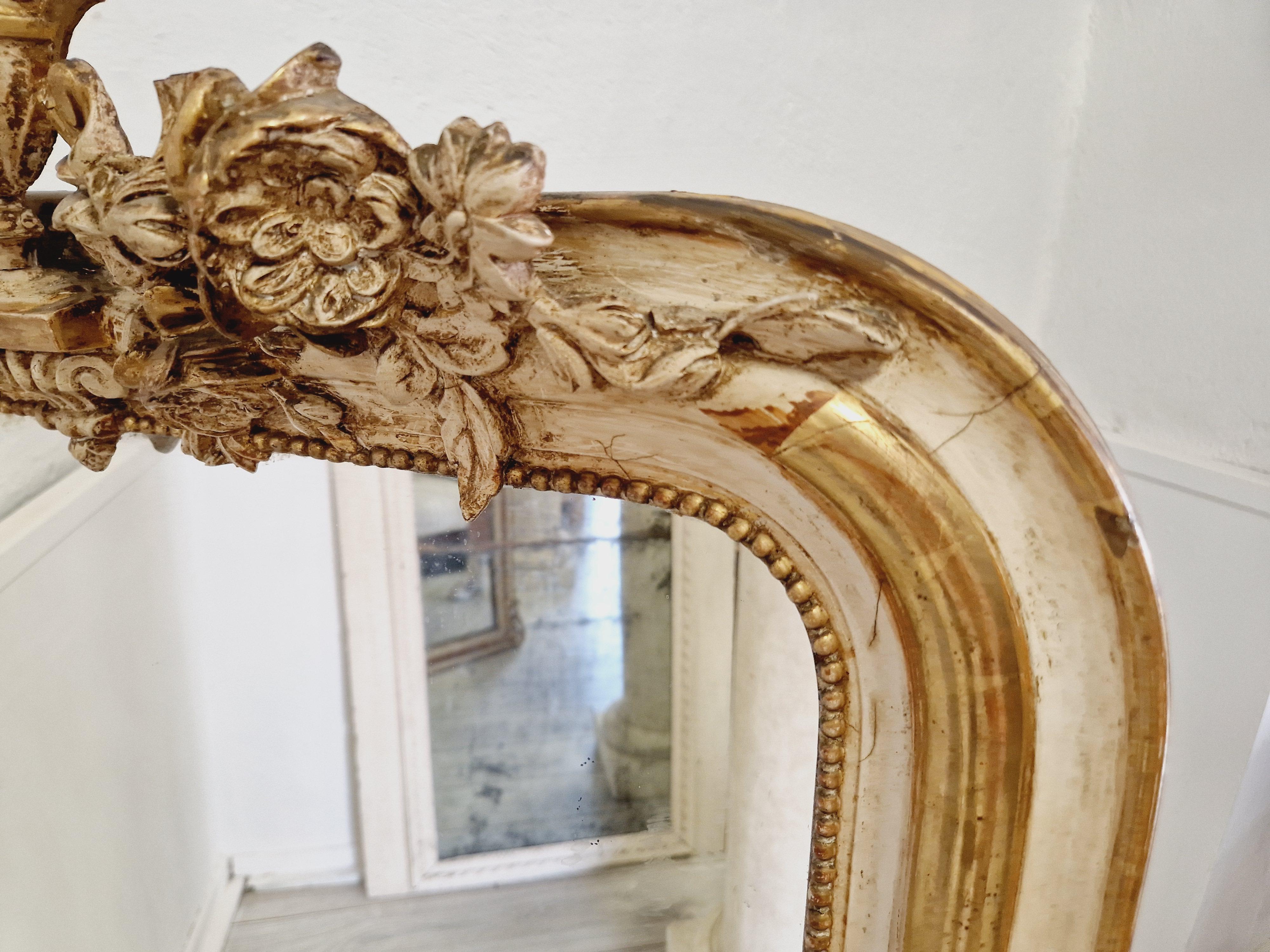 Questo bellissimo specchio è in stile Luigi XVI e risale al 1870 circa. La superficie dello specchio presenta una vecchia cornice in legno bianco (crema) e dorato e la lastra di vetro originale; è presente un bellissimo stemma a bouquet floreale,