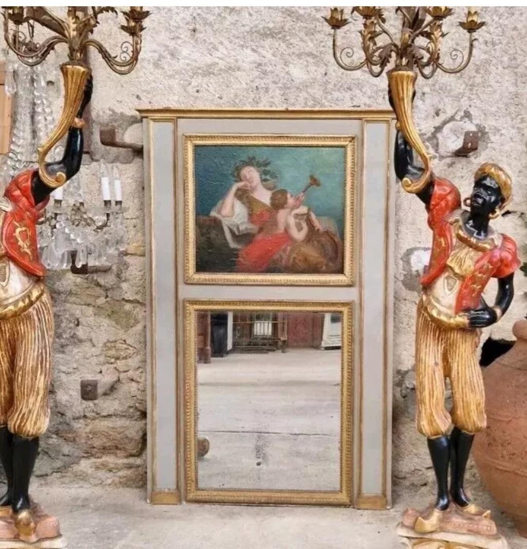 Ce miroir français ancien est orné d'une superbe peinture à l'huile du XIXe siècle sur son panneau central, représentant une femme avec un ange musicien. Le miroir est de forme rectangulaire avec un contour gris et une finition dorée. Il est fixé au