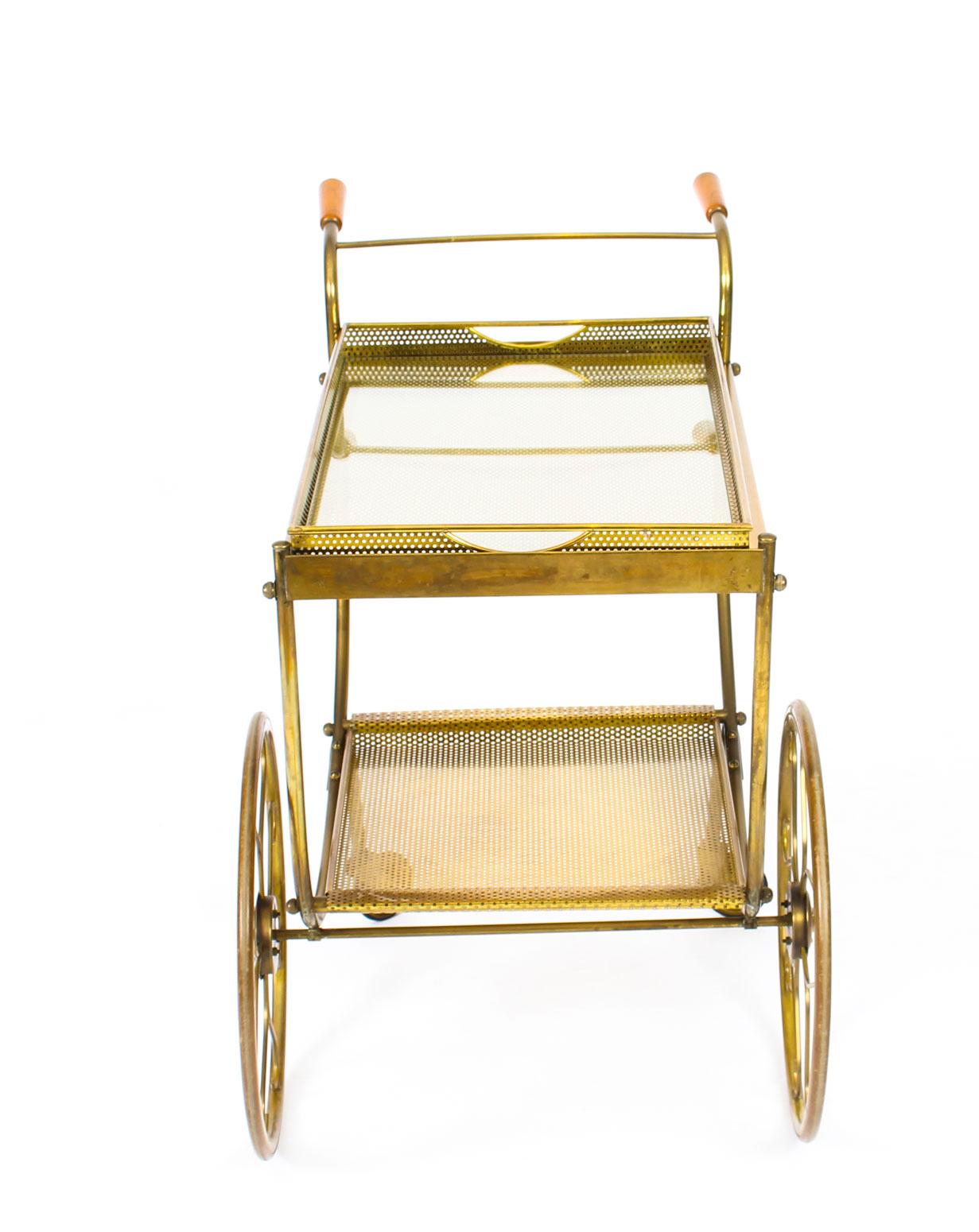 This is a striking antique French modernist gilt two-tier drinks trolley, circa 1970 in date.

The trolley is of rectangular form and features a two handled glass serving tray which lifts out, on top with a smaller tray below for bottles,