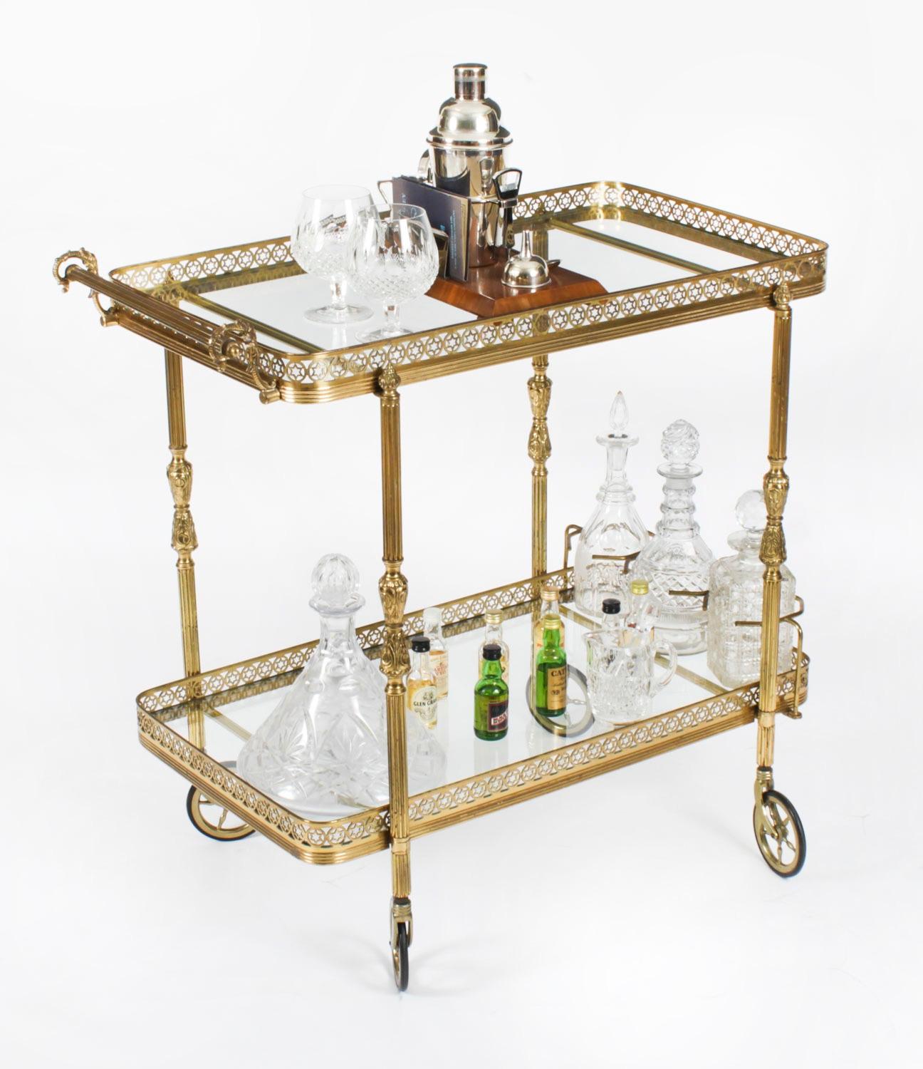 This is a striking antique French Modernist gilt two-tier drinks trolley, circa 1950 in date.

The trolley is of rectangular form with a hanlde and features a pierced galleried glass serving tray with another below with fixtures for three