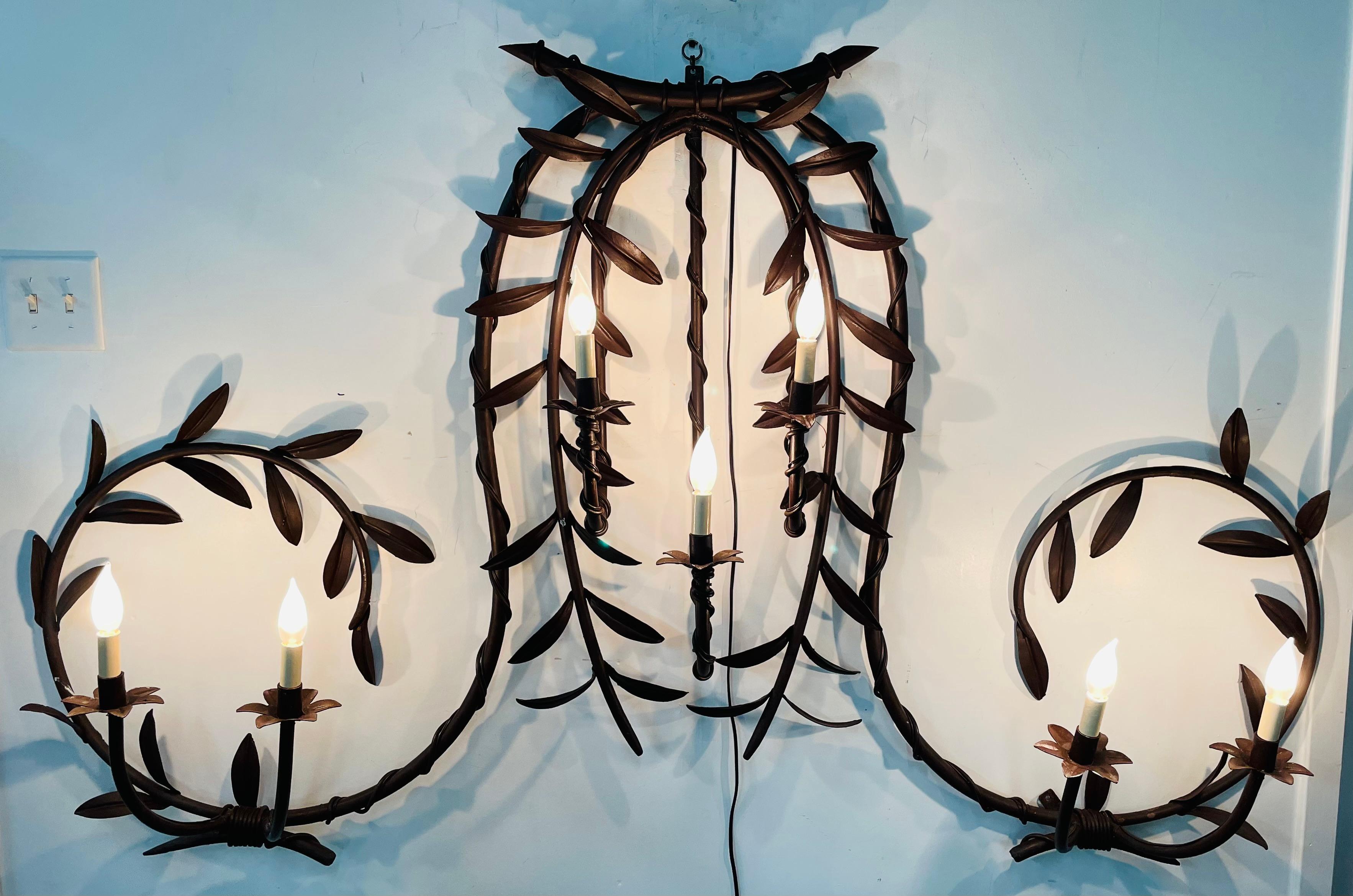 A majestic early 20th century wrought iron wall scone finely hand carved and featuring hanging leaves. The sconce holds 7 candelabra bulbs and was recently wired. The two tone light antique French wrought iron leaves design sconce will look amazing