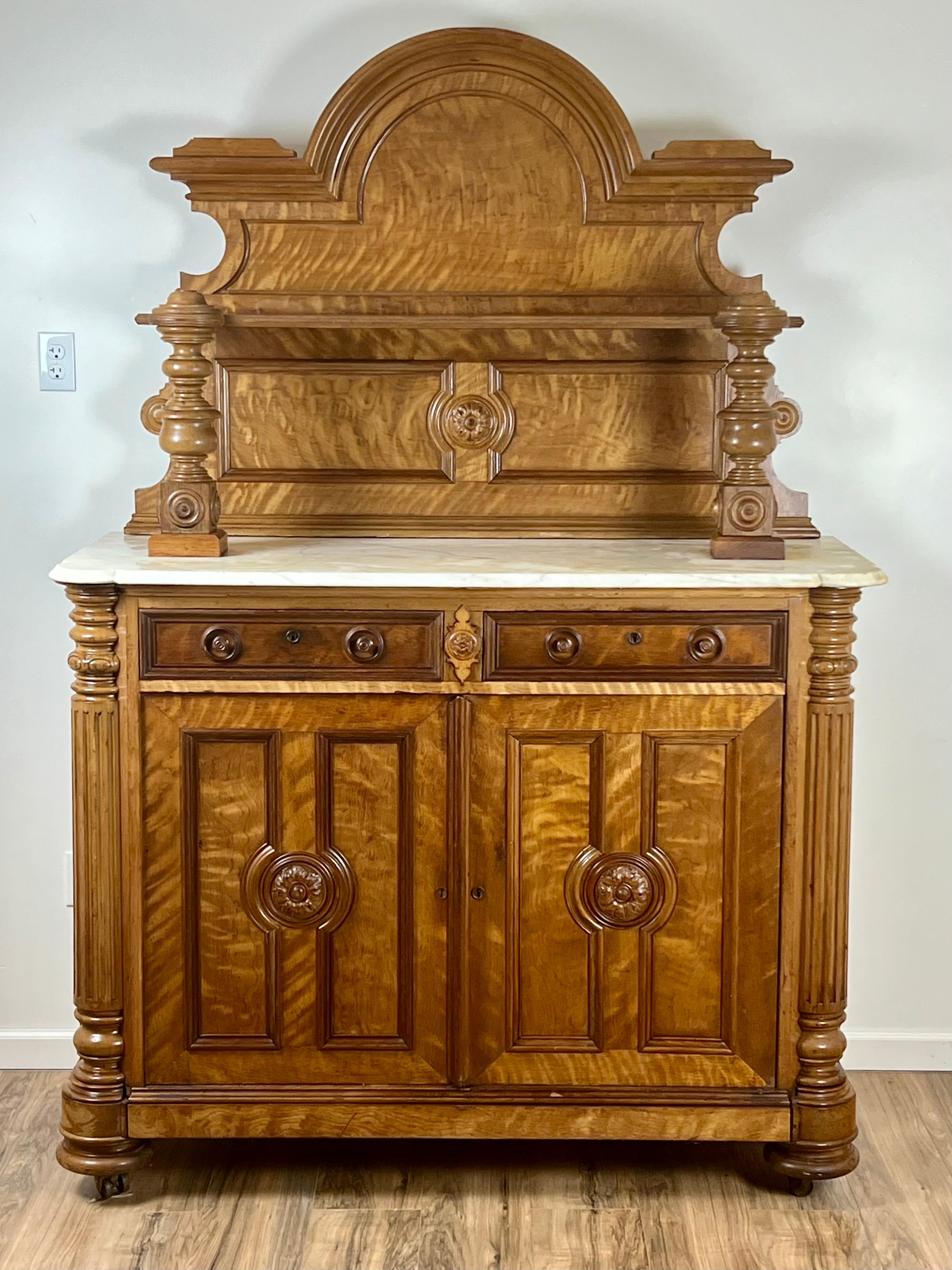 Questo buffet francese Napoleone III della metà del XIX secolo, realizzato in noce riccio, esemplifica il design sofisticato e la meticolosa lavorazione artigianale dell'epoca. La parte superiore del buffet è coronata da un frontone ornato e