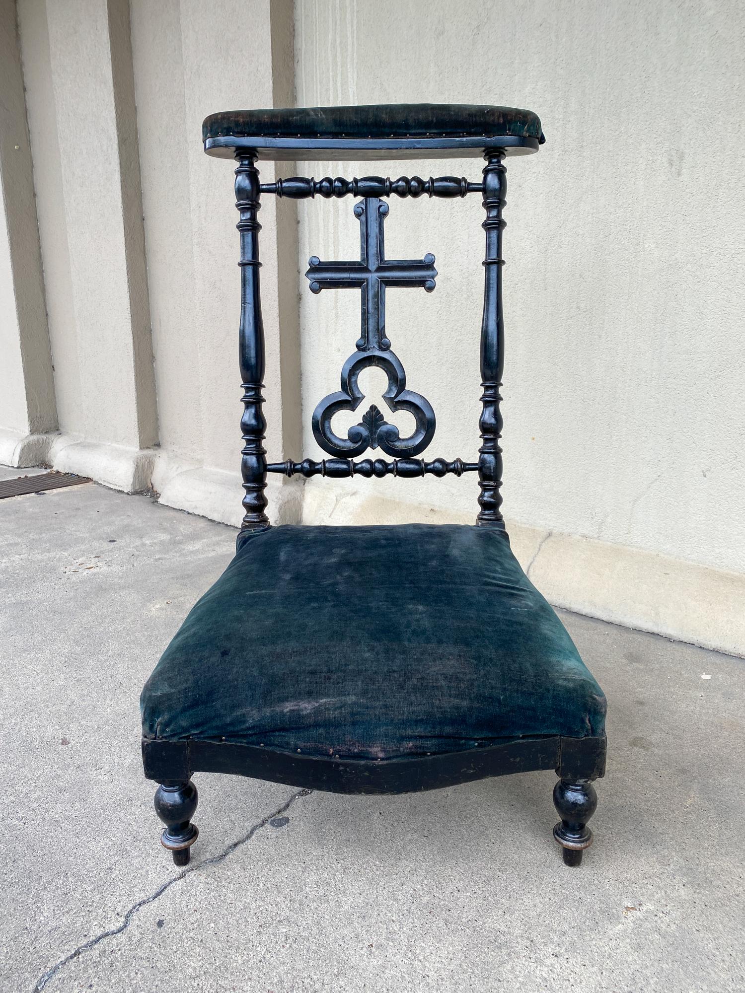 This antique French Napoleon III kneeler chair dates to 1850 and is crafted in ebonized wood and deep green velvet upholstery. With ornate carvings on the back of the chair, featuring a cross, trefoil design along with turned details on the side and